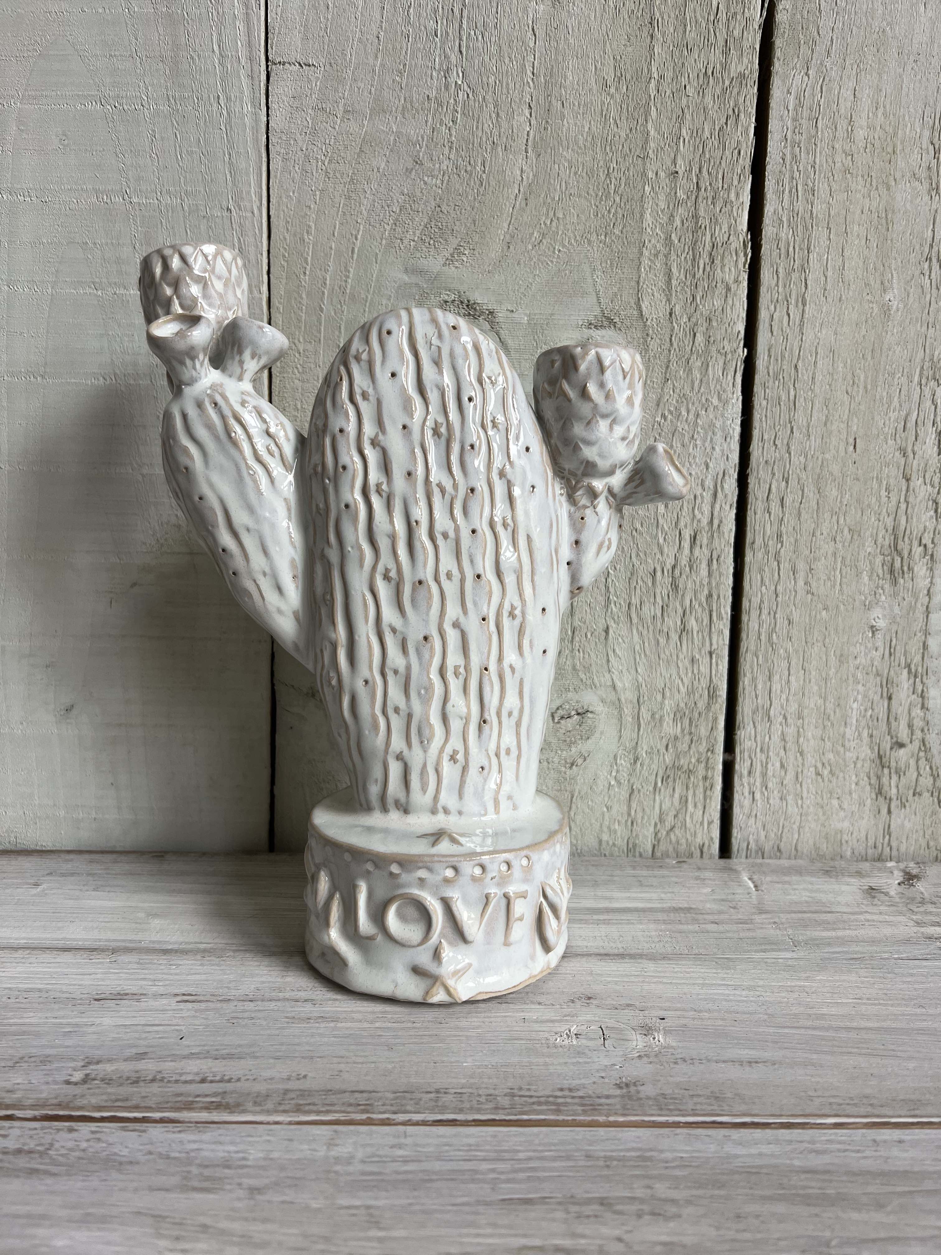 Handmade white ceramic cactus candle holder with textured detailing and "LOVE" embossed base displayed on a rustic wooden shelf.