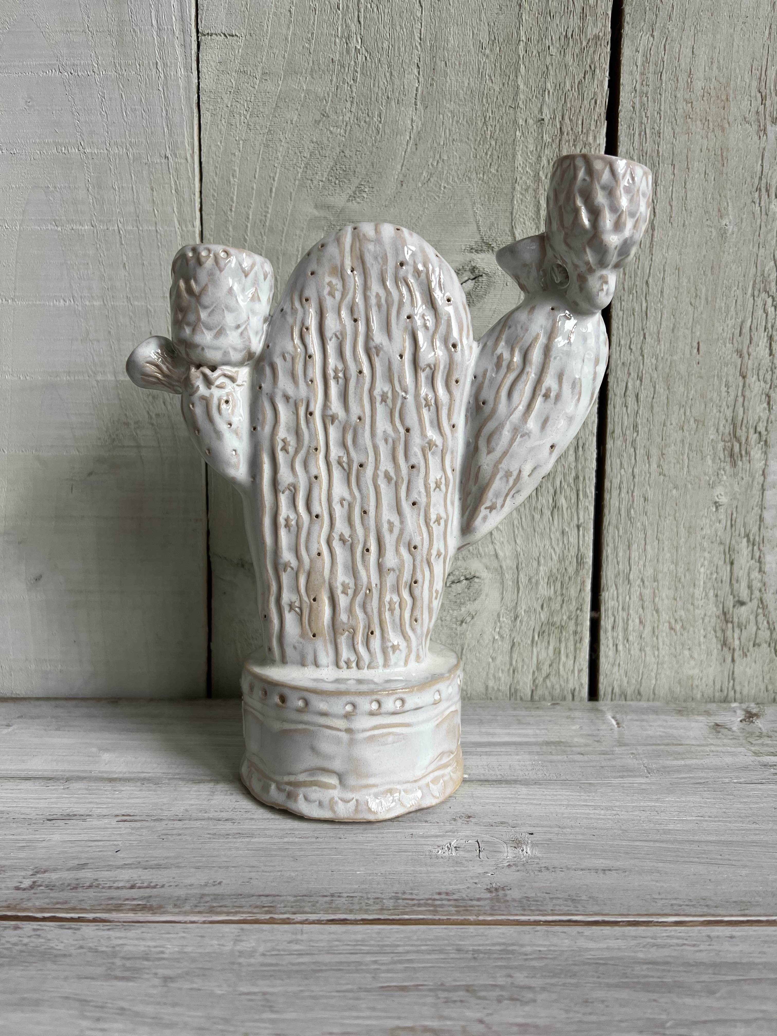 White handmade ceramic cactus candle holder with textured finish standing on a rustic wooden shelf.