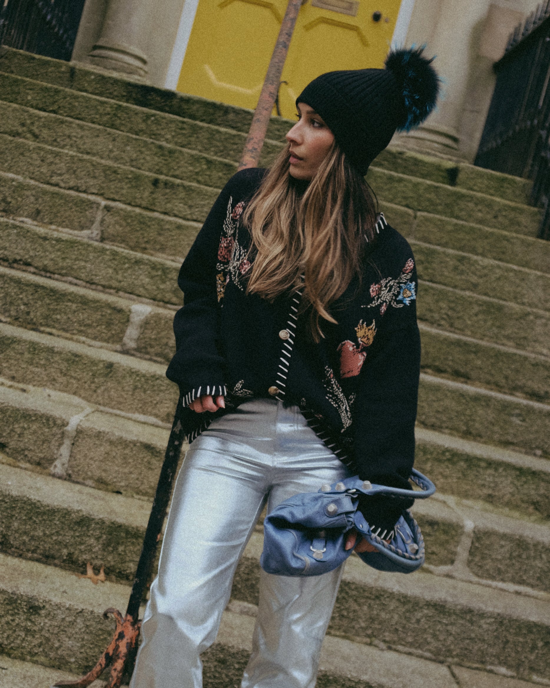 Front view of a person wearing a black knit cardigan featuring a heart, flowers, birds, and sun knit design.