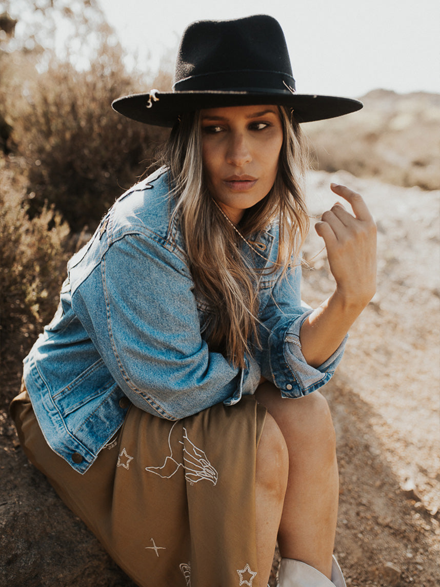 Light blue denim jacket with "Follow Your Bliss" embroidered front design, floral embroidery, and celestial motifs, shown from the front.