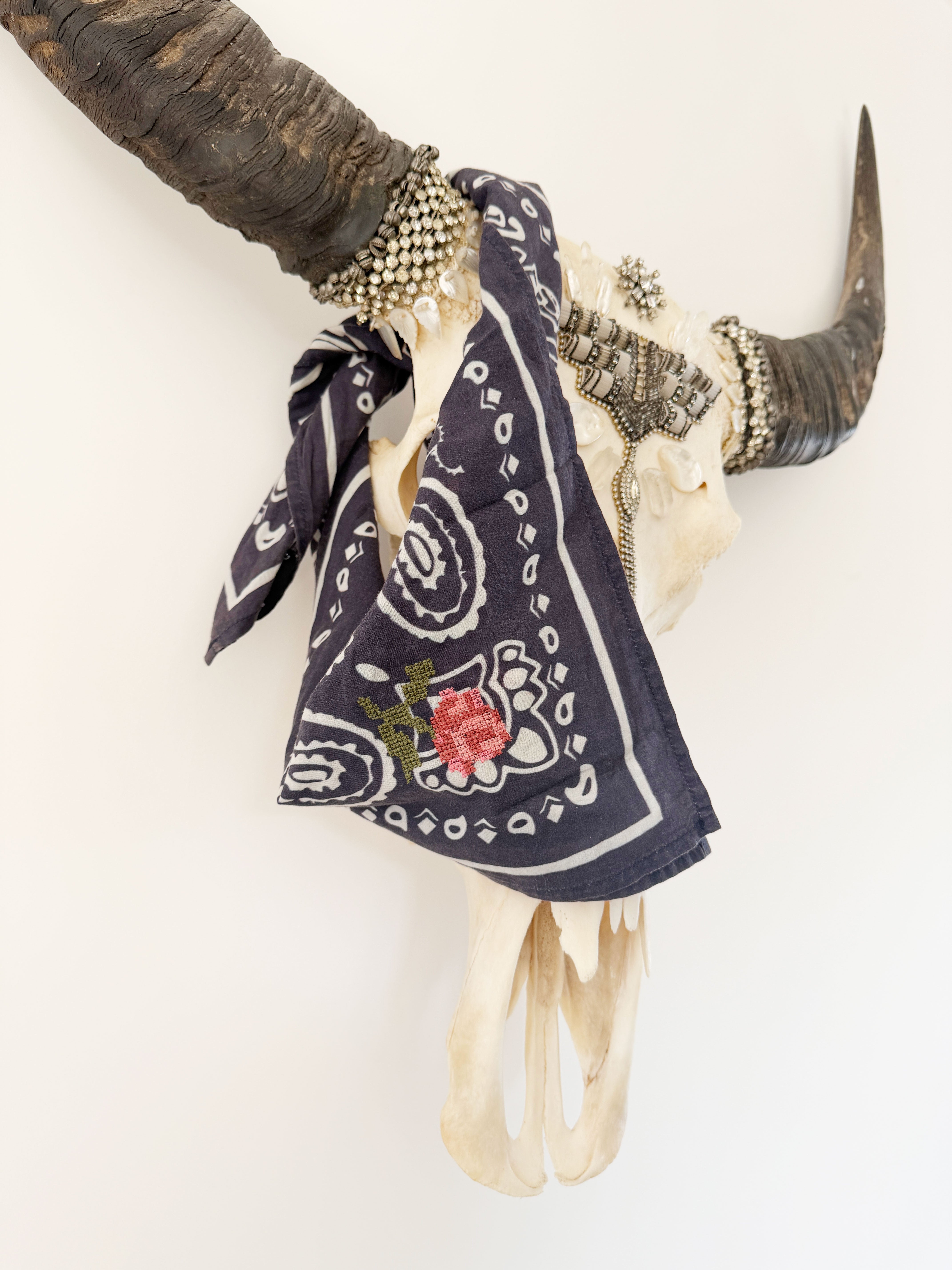 Navy bandana print scarf with rose embroidery tied around decorative horns.