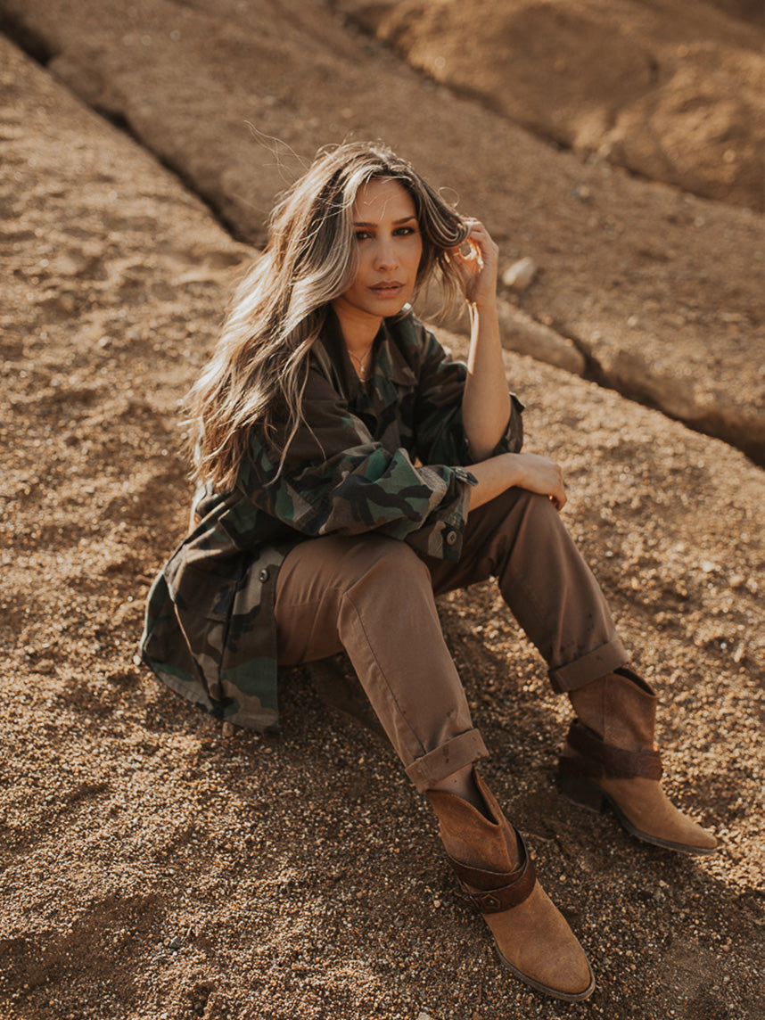 Camouflage military jacket, shown from the front in a seated lifestyle image.