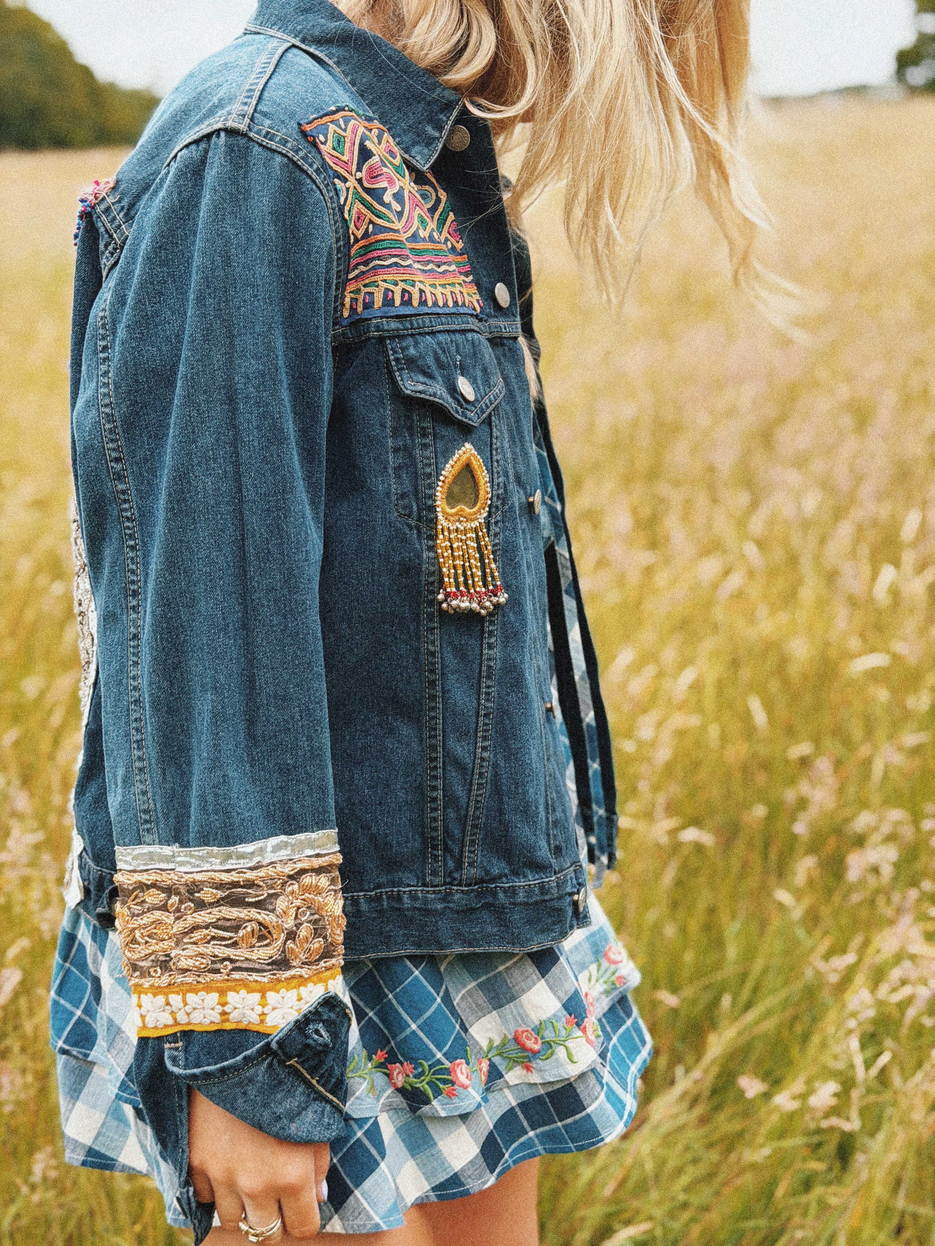 Side view of a blue denim jacket with colourful embroidered on the arms