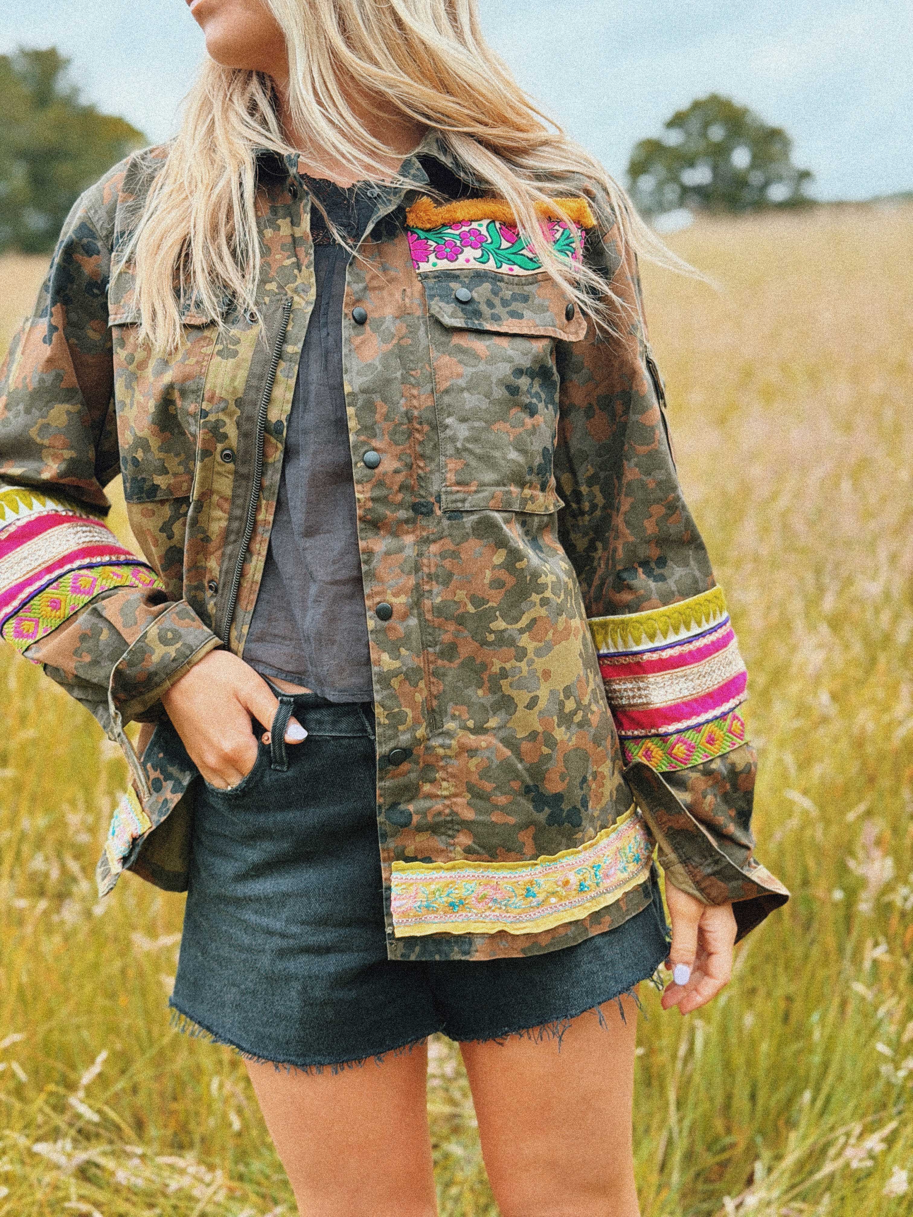 Embellished camouflage jacket with colourful embroidered sleeve panels, decorative hem trim, and chest detail, front view.