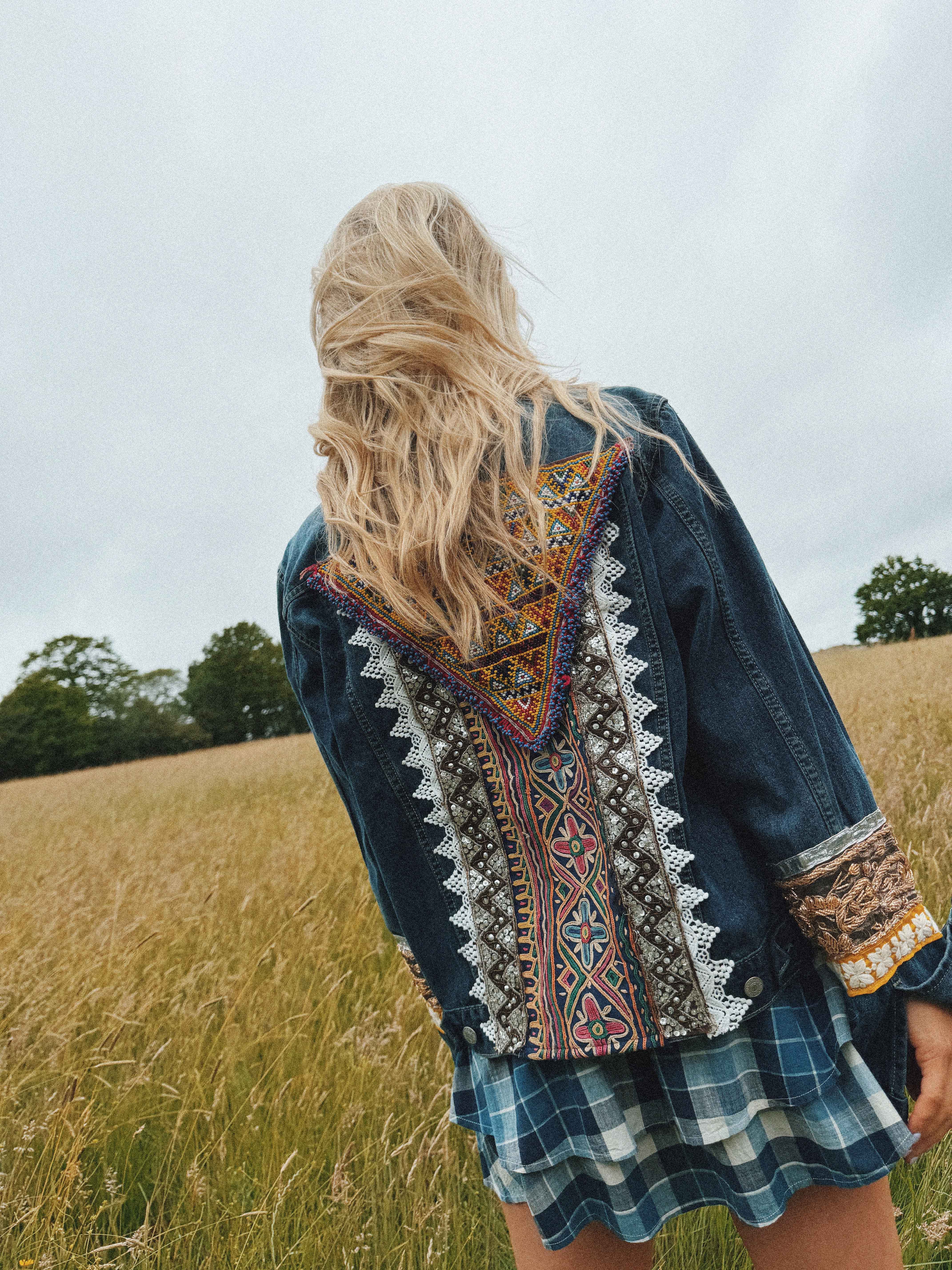 Back view of a blue denim jacket with colourful embroidered back panel.