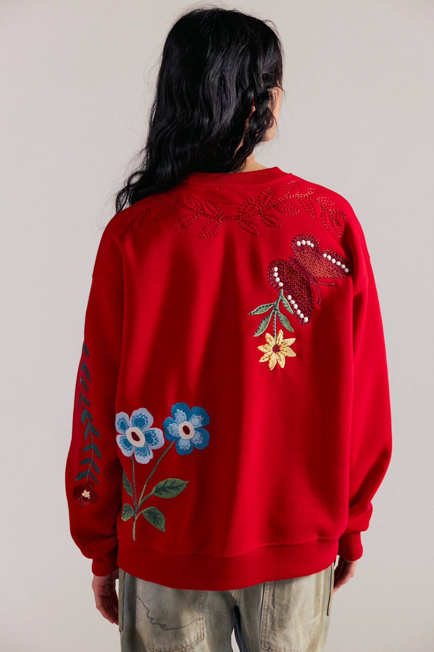 Back view of a red sweatshirt with embroidered flowers and a butterfly motif.