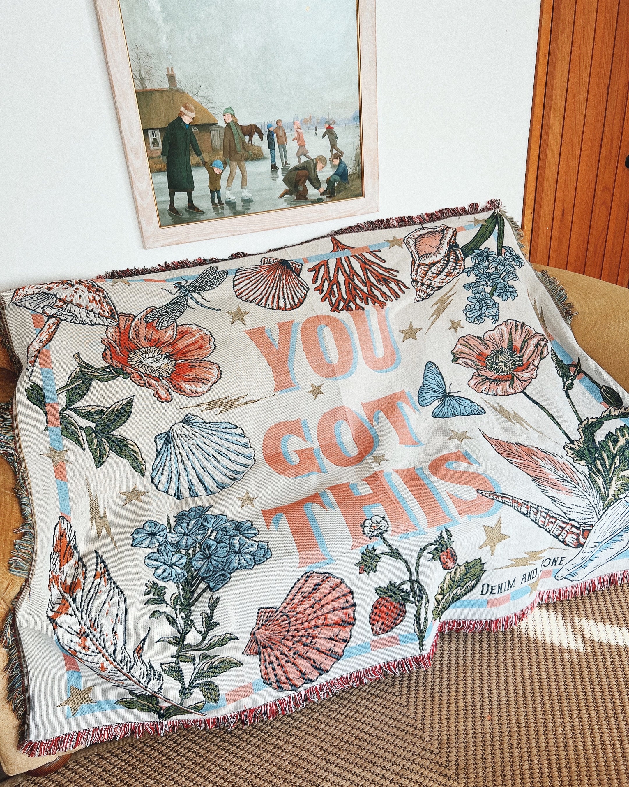 "You Got This" woven throw blanket draped over a sofa in a cosy living room.
