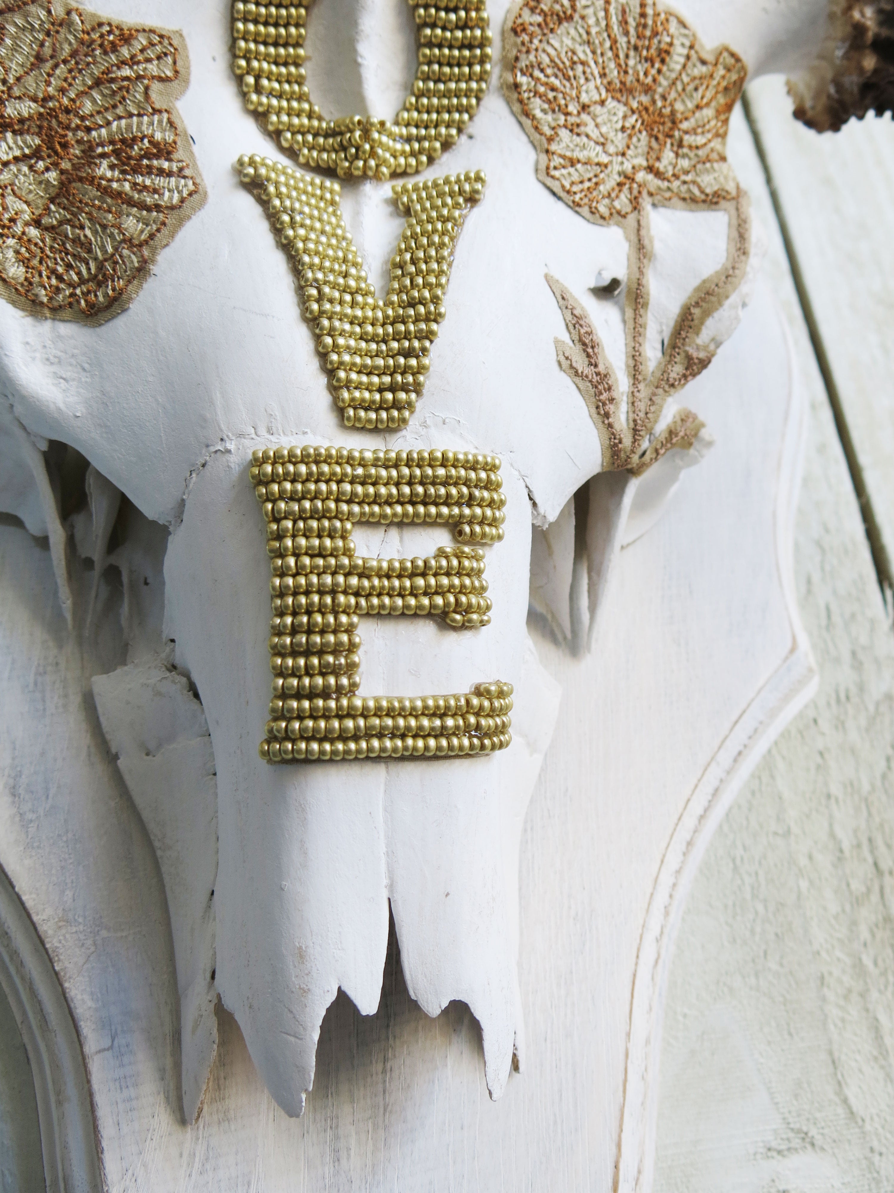 Close-up of decorative moose skull with gold beaded LOVE lettering and botanical embellishments.