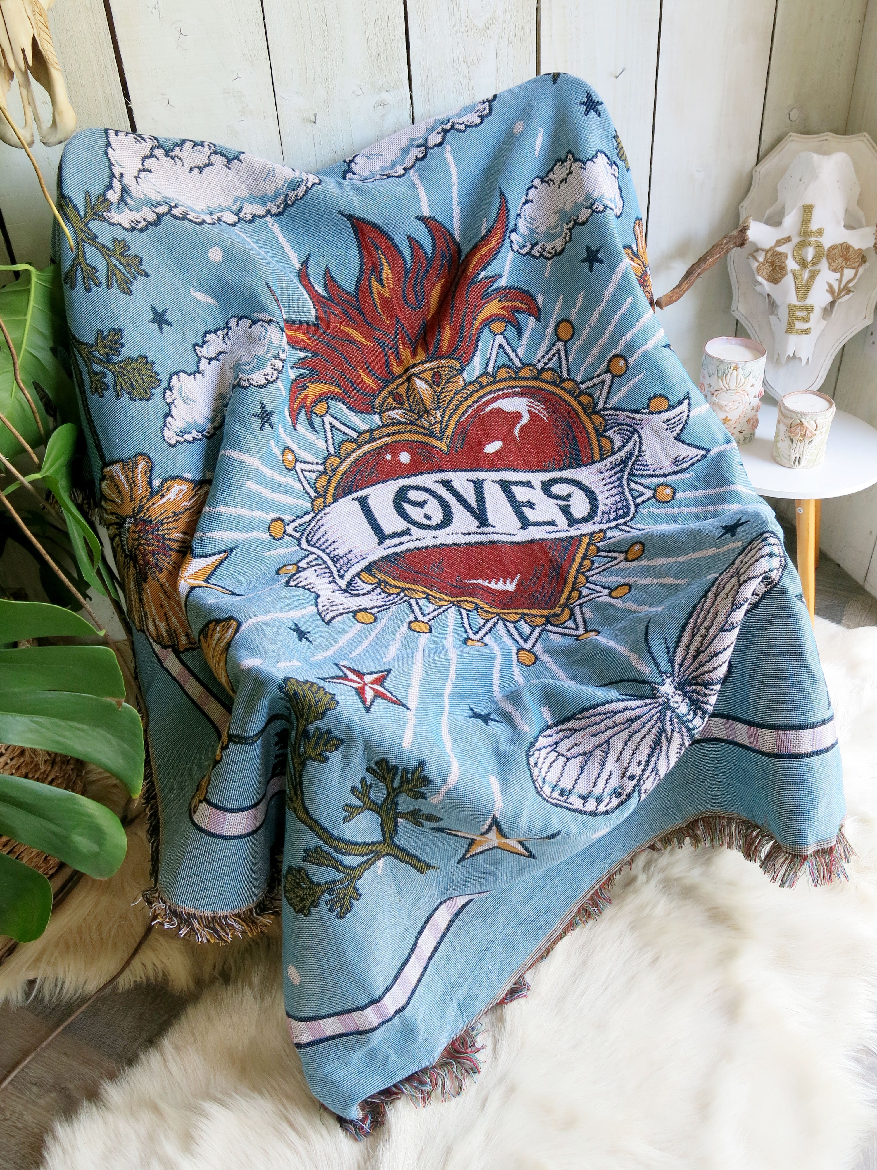 Light blue "Loved" woven throw blanket draped over an armchair in a cosy living room.