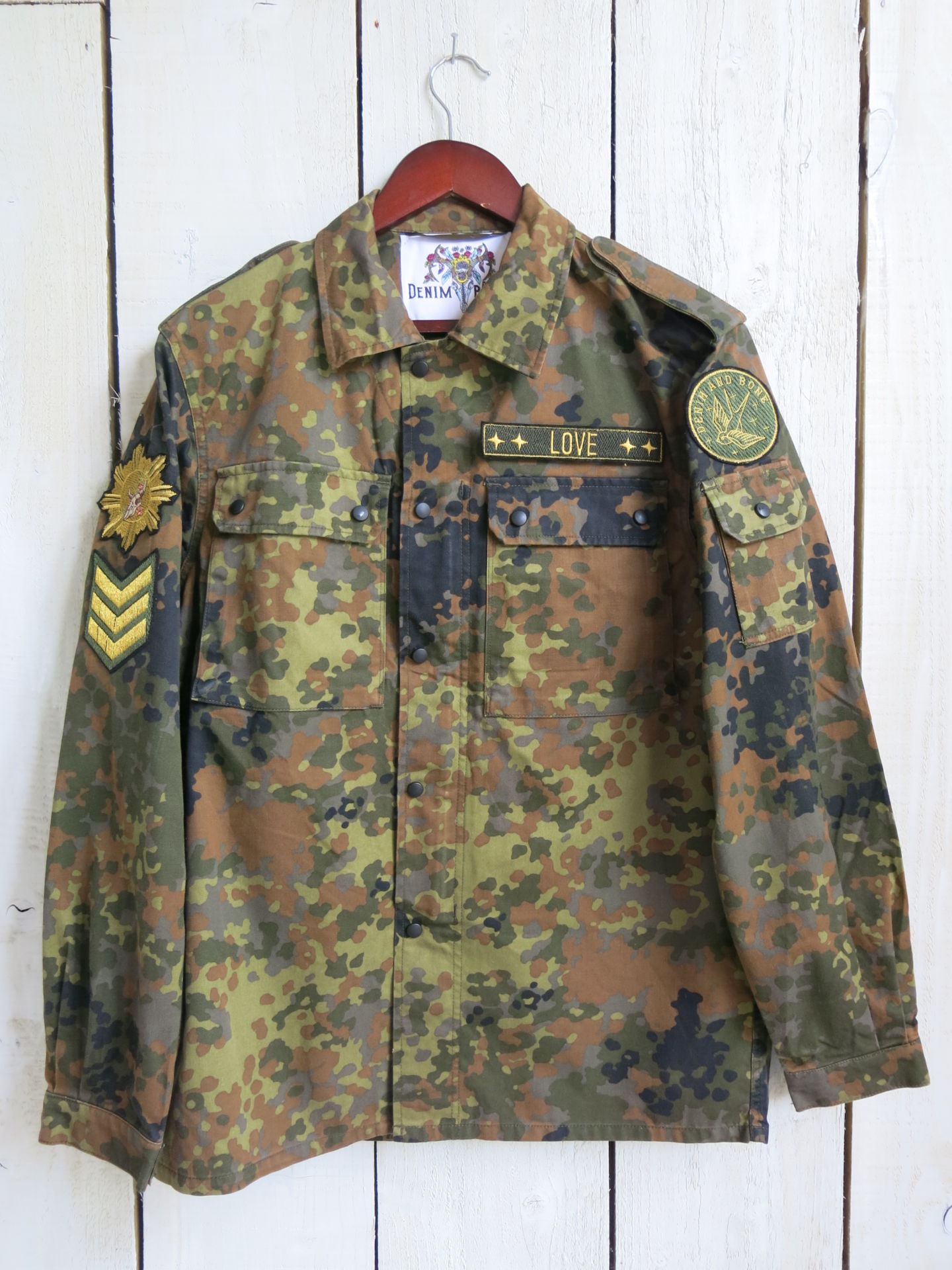 Camouflage military jacket with decorative patches and "LOVE" chest embroidery, front view.