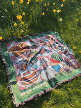 Colorful quilt with food illustrations on a grassy field with daffodils