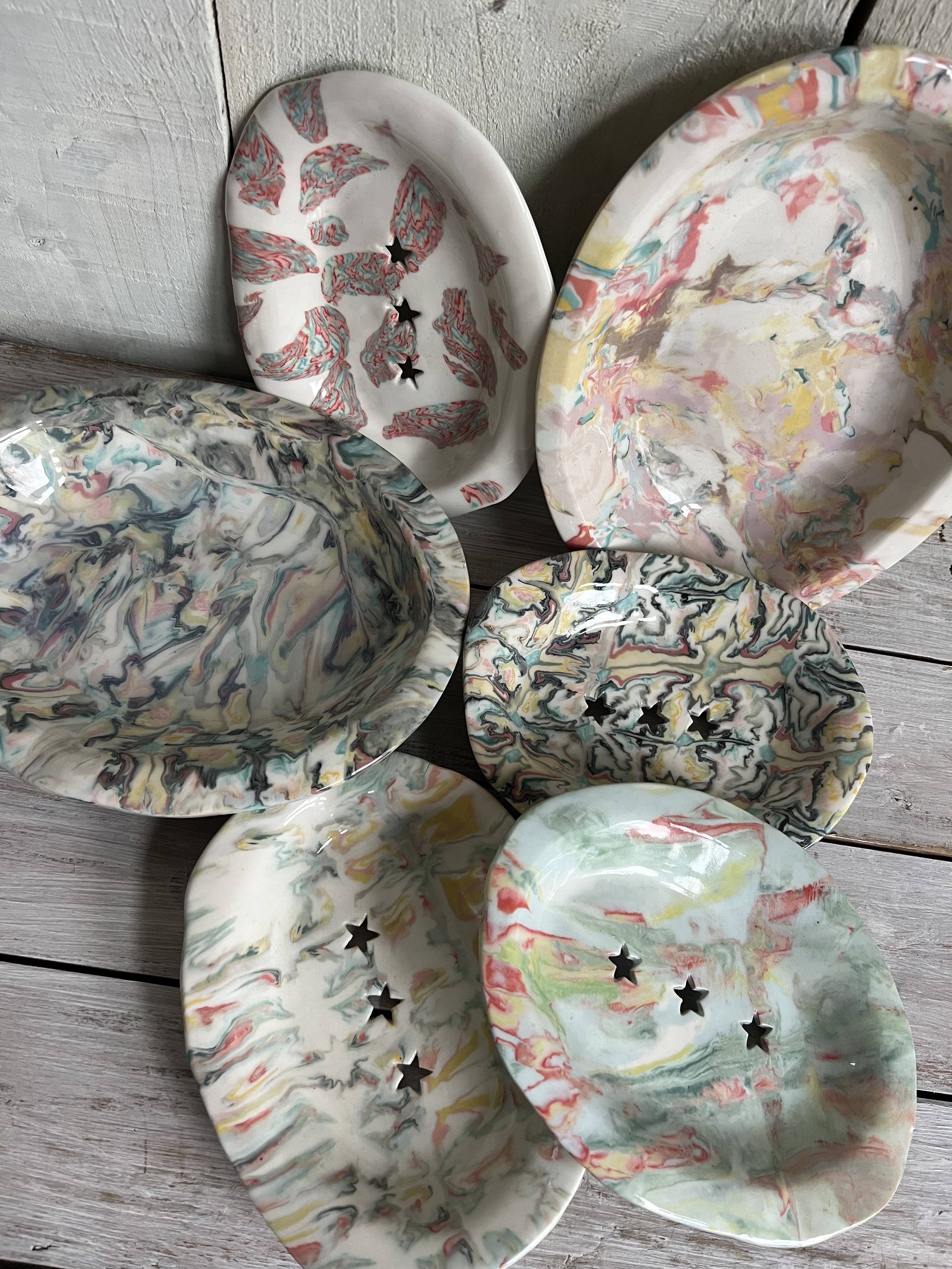 Collection of handmade ceramic trinket dishes with marbled and patterned glazes, including decorative star-shaped cut-outs.
