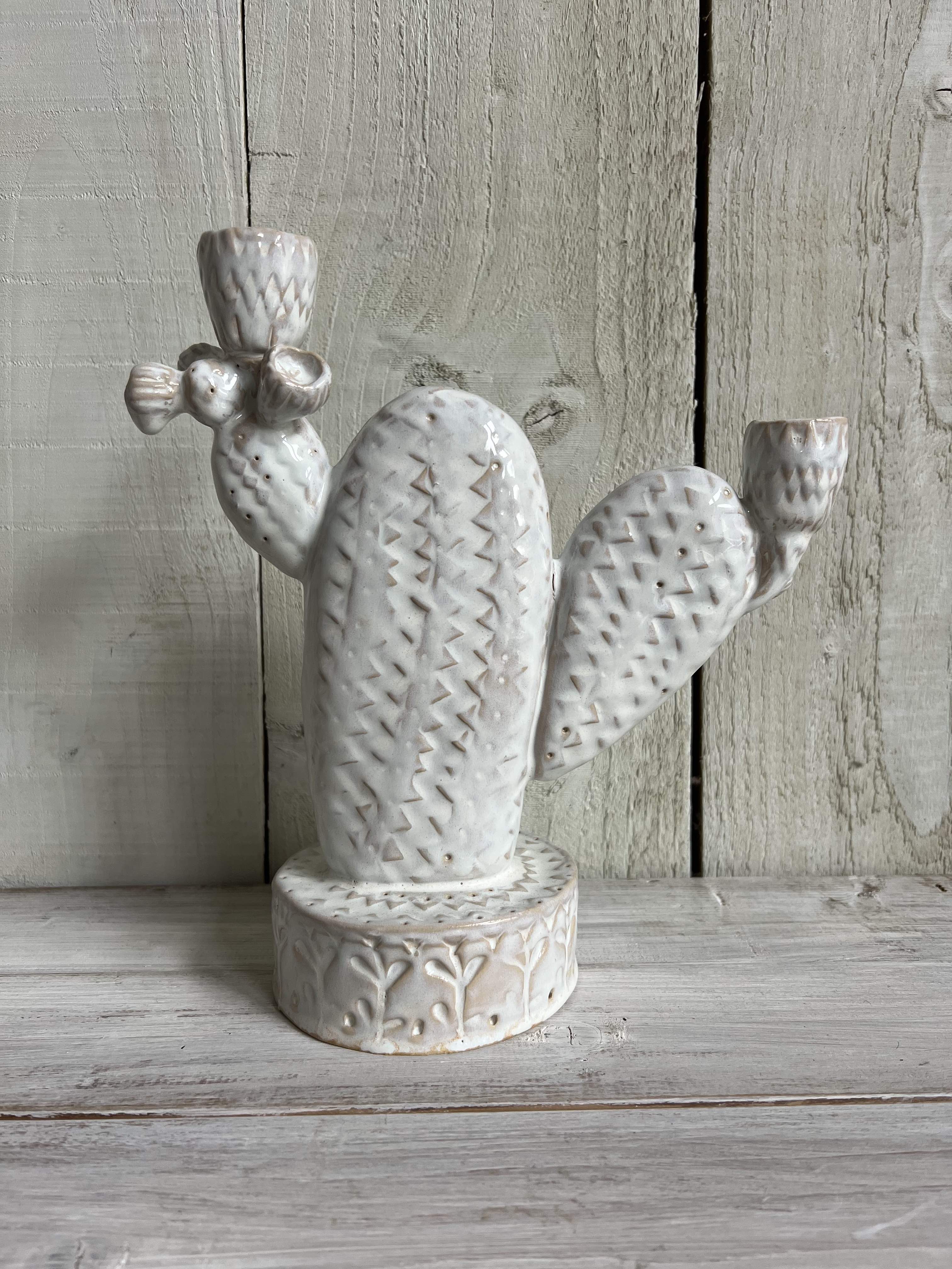 White handmade ceramic cactus candle holder with textured finish standing on a rustic wooden shelf.