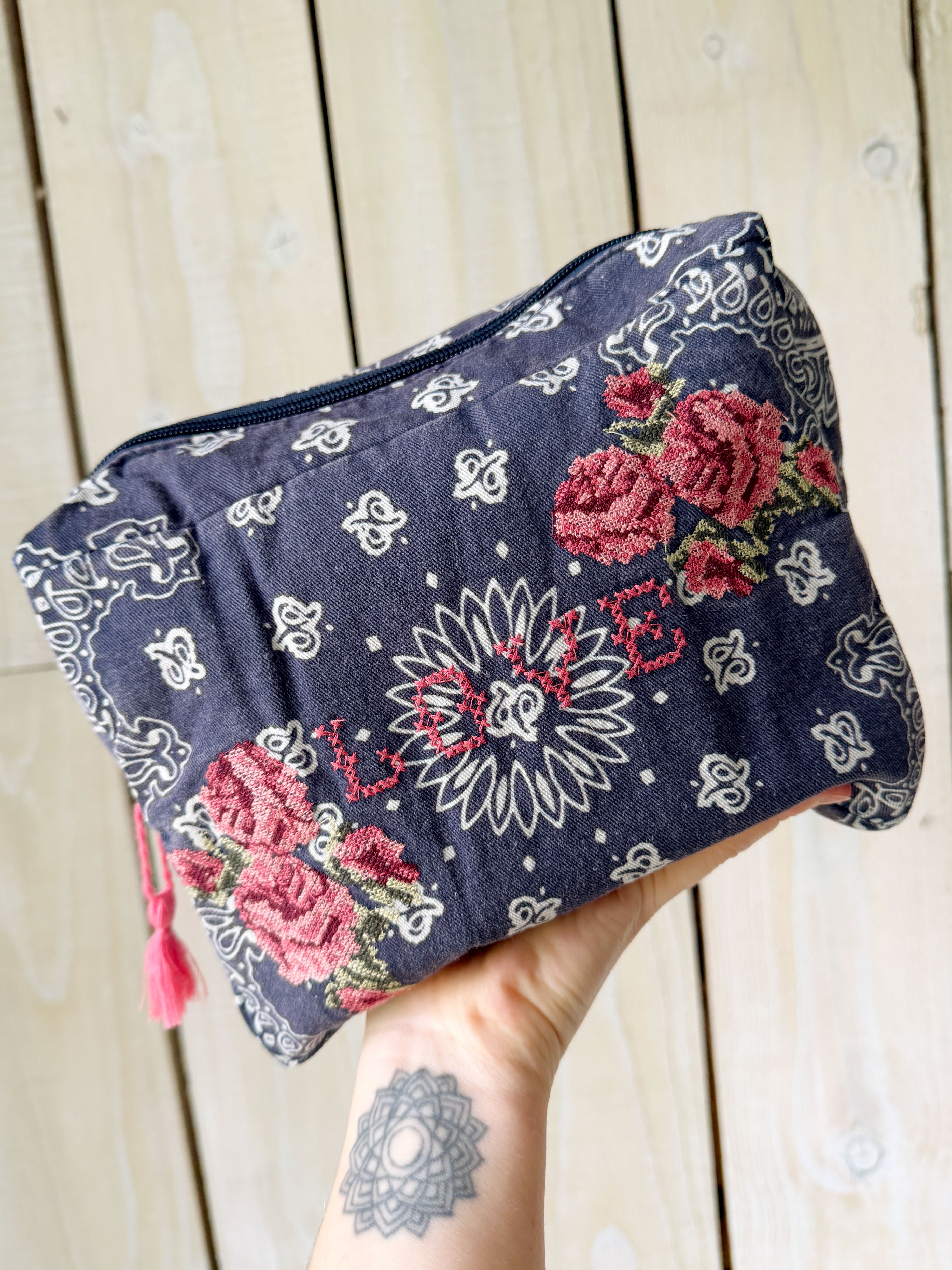 Navy bandana print canvas cosmetic bag embroidered with cross stitch roses and the word "LOVE."