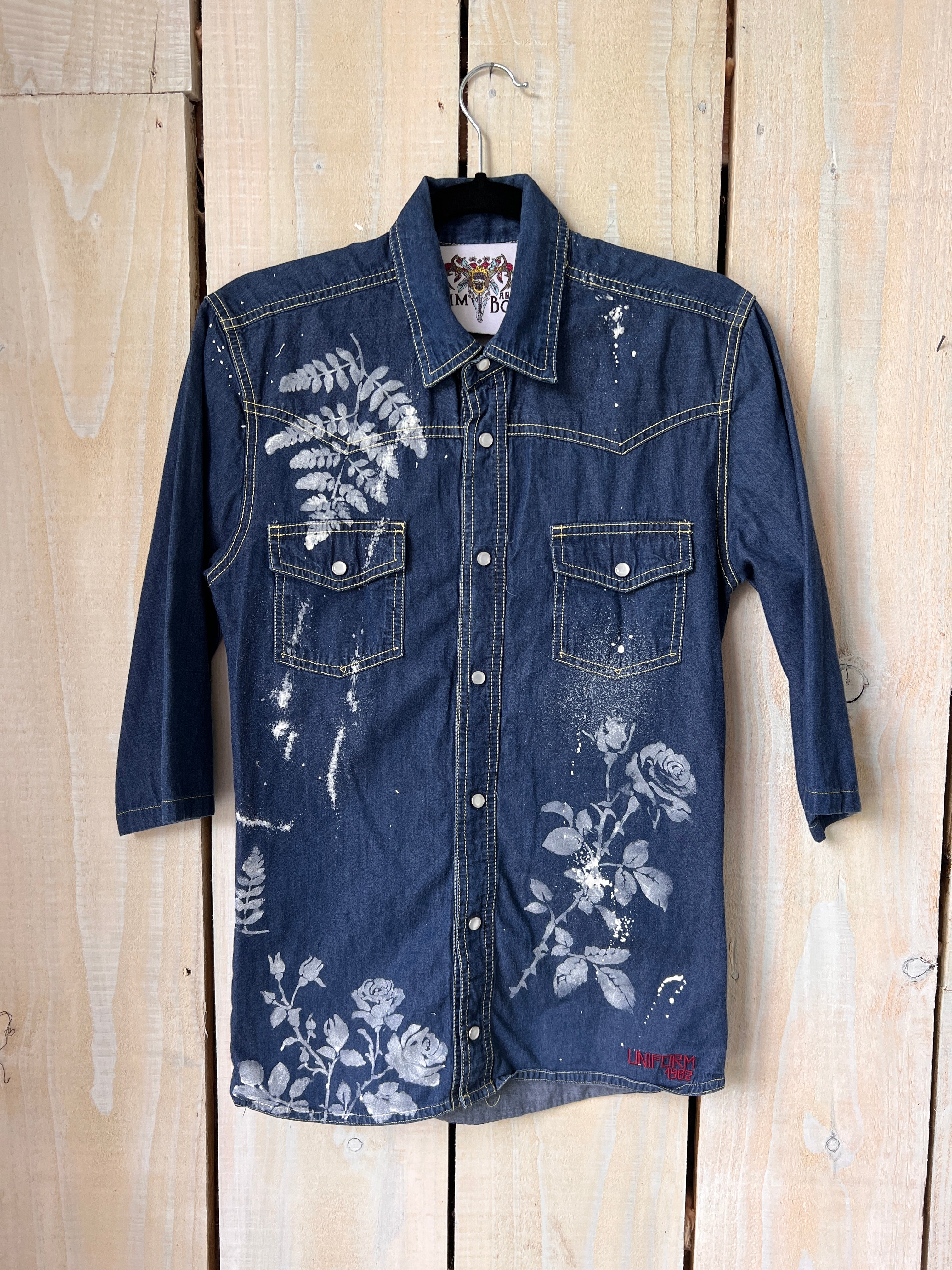 blue denim shirt with hand-painted white floral and butterfly artwork.
