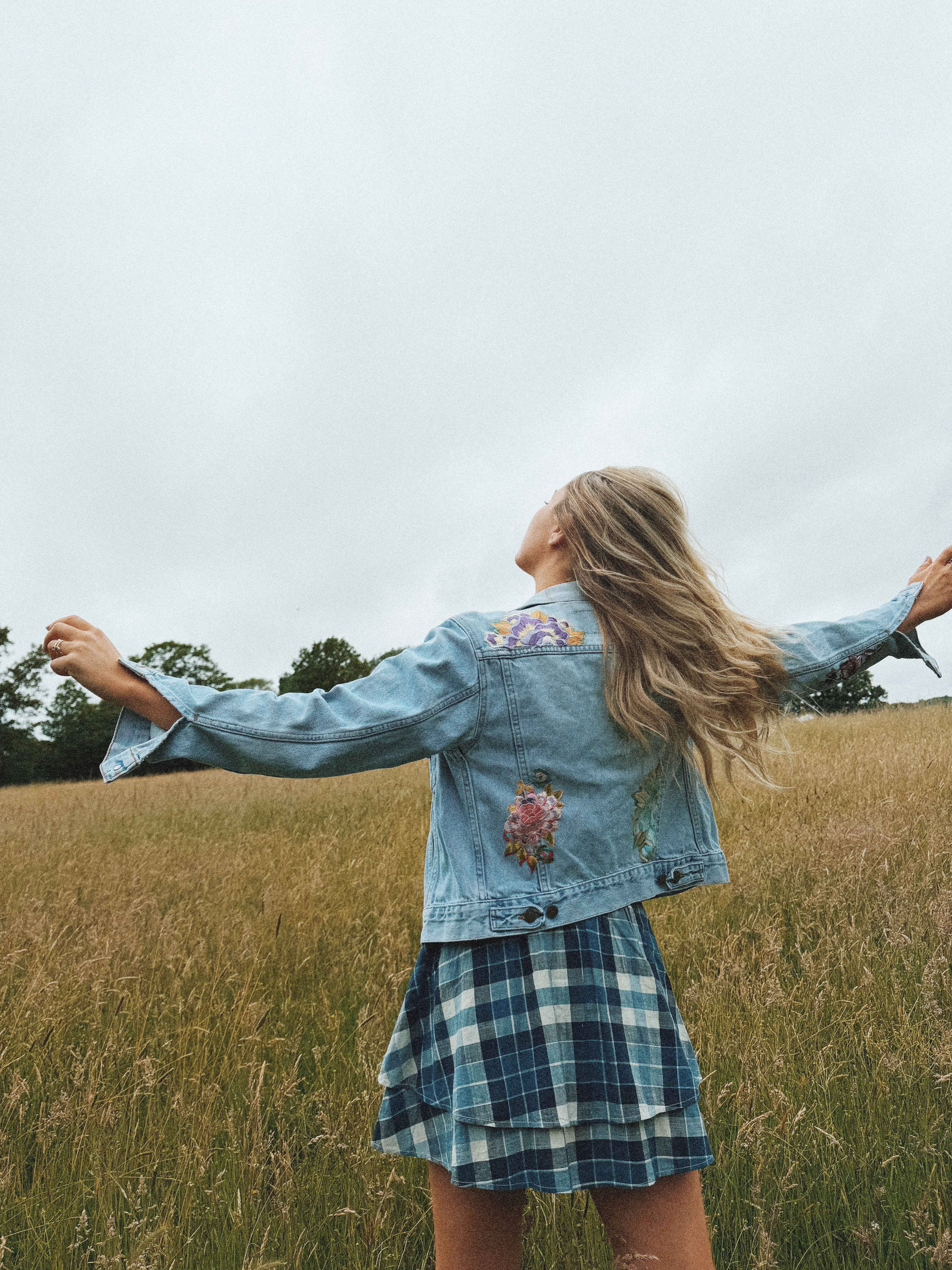 Light blue denim jacket with colourful vintage textile patchwork on the back, shown from the rear.