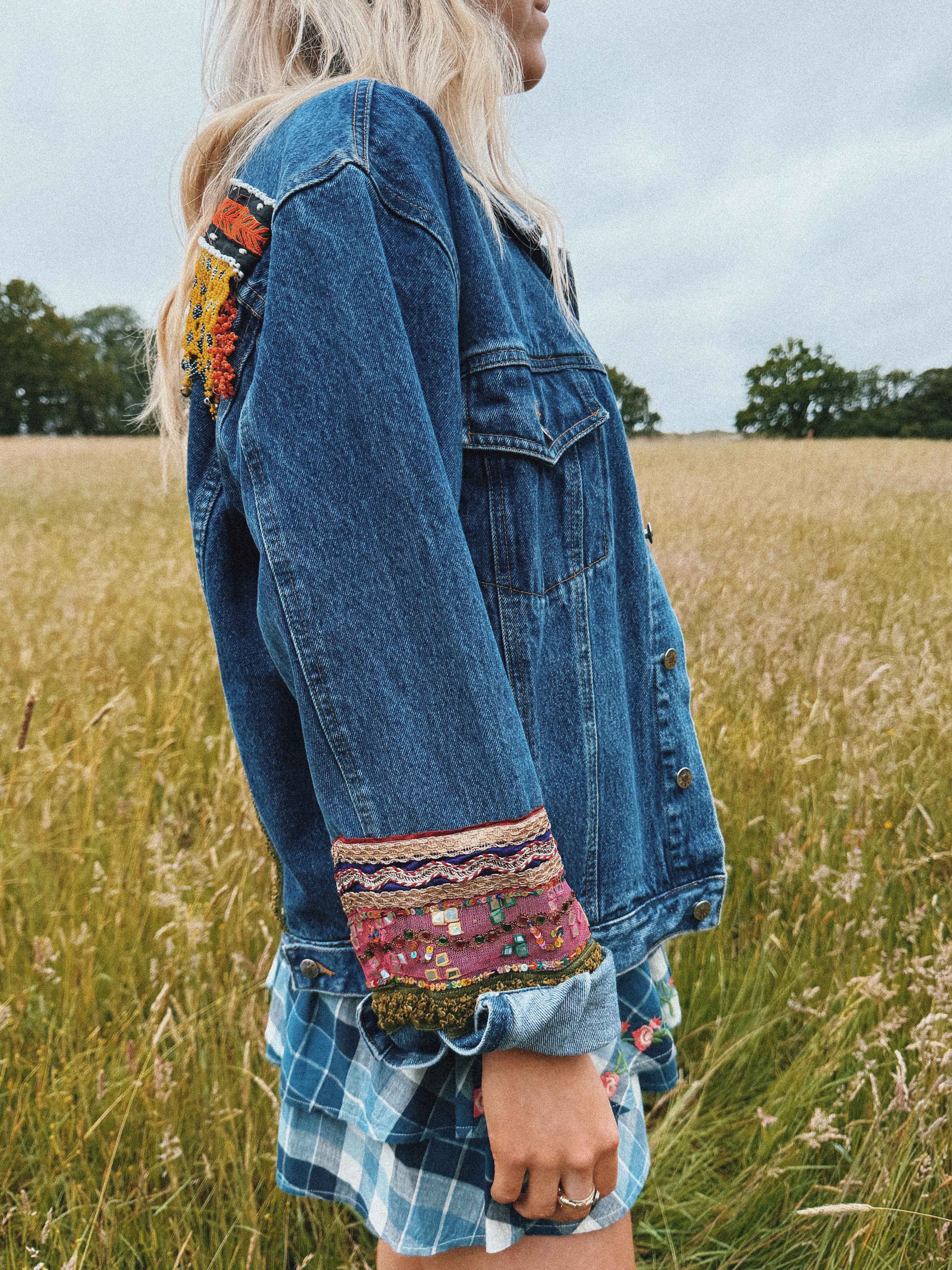 Dark blue denim jacket featuring a colourful embroidered decorative sleeve cuffs. sideview