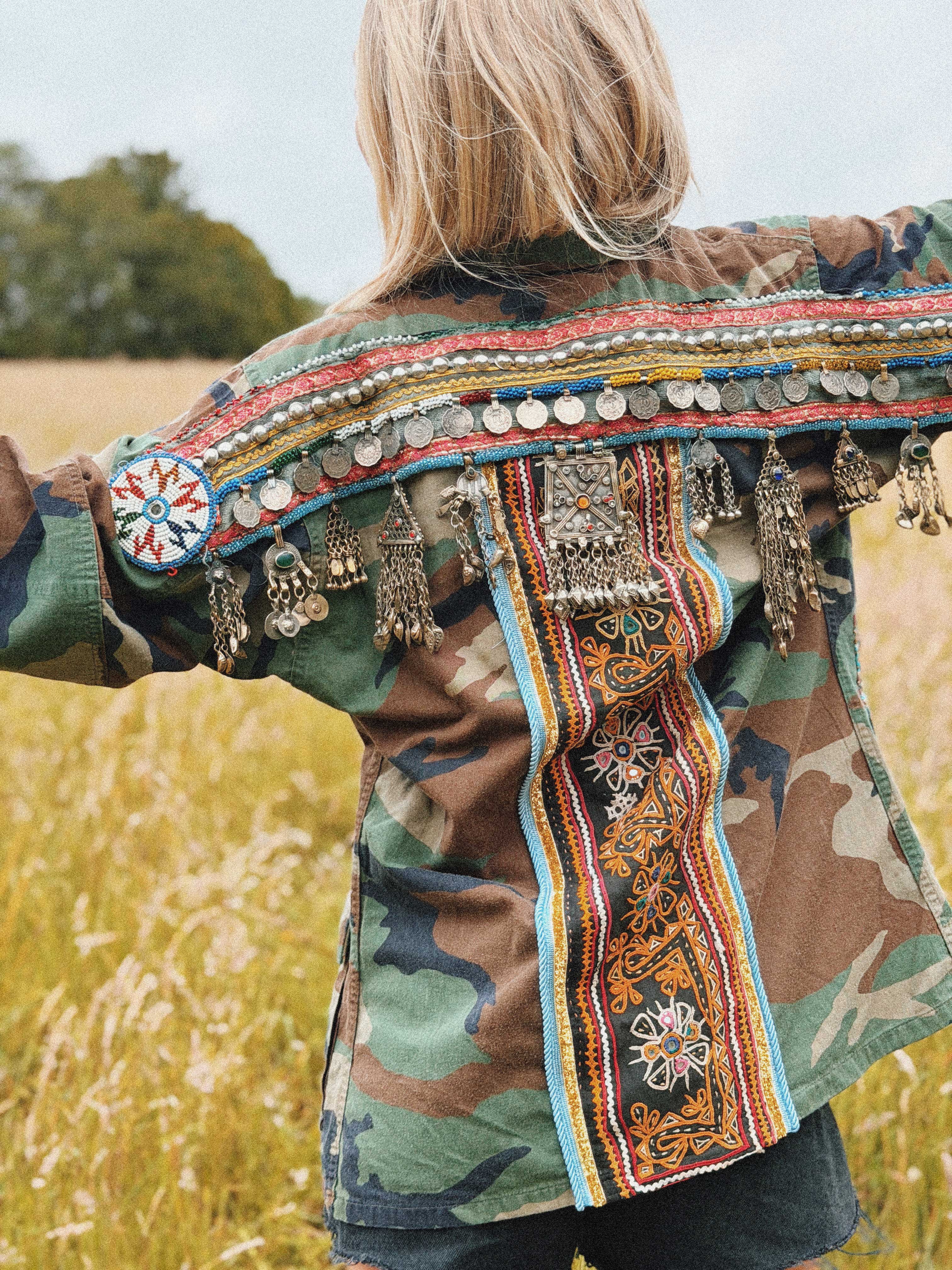 Embellished camouflage jacket with coin trim, embroidered back panel, and decorative tassels, shown from the back.