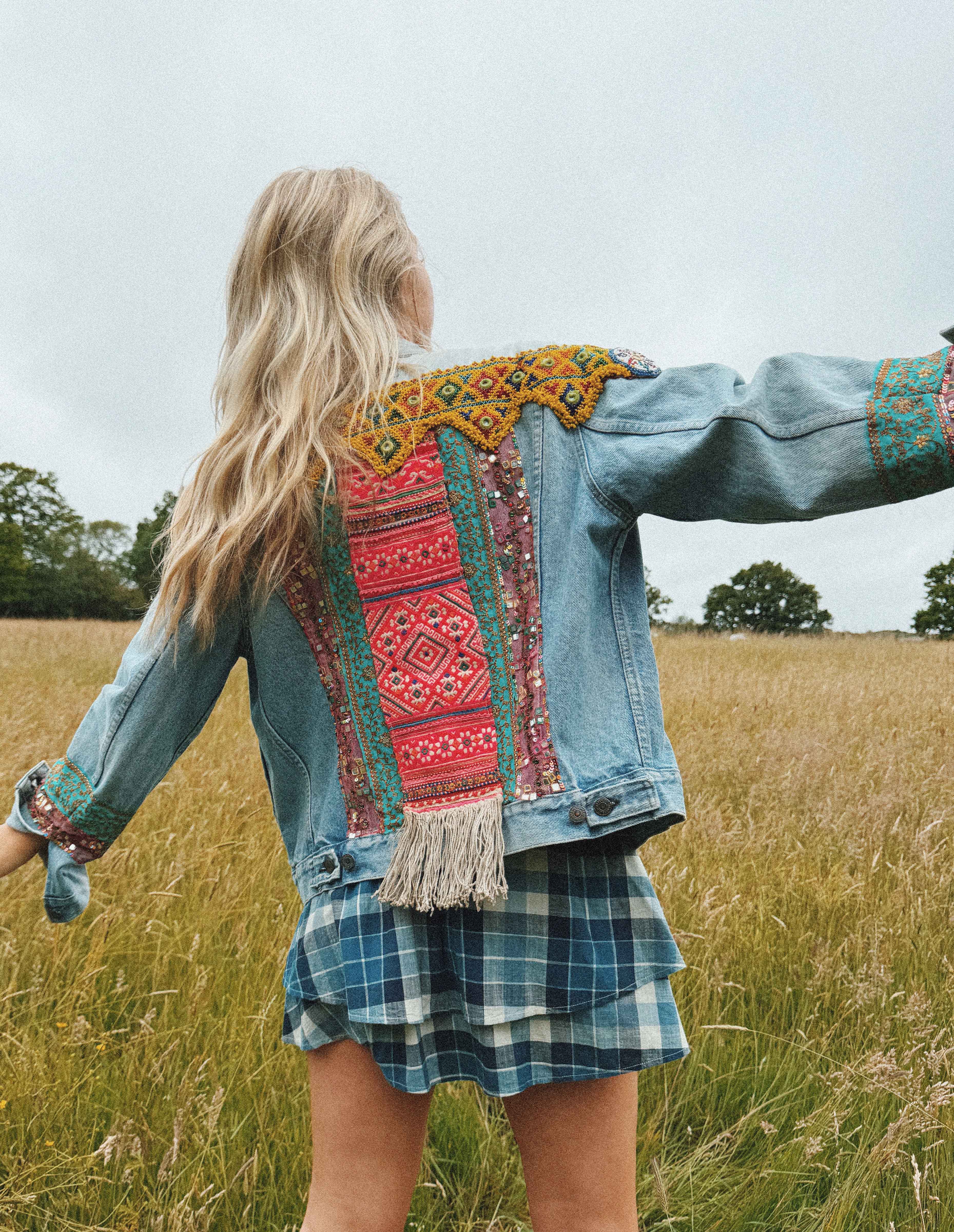 Light blue denim jacket with colourful embroidered back panel and beaded shoulder detail, shown from the back.