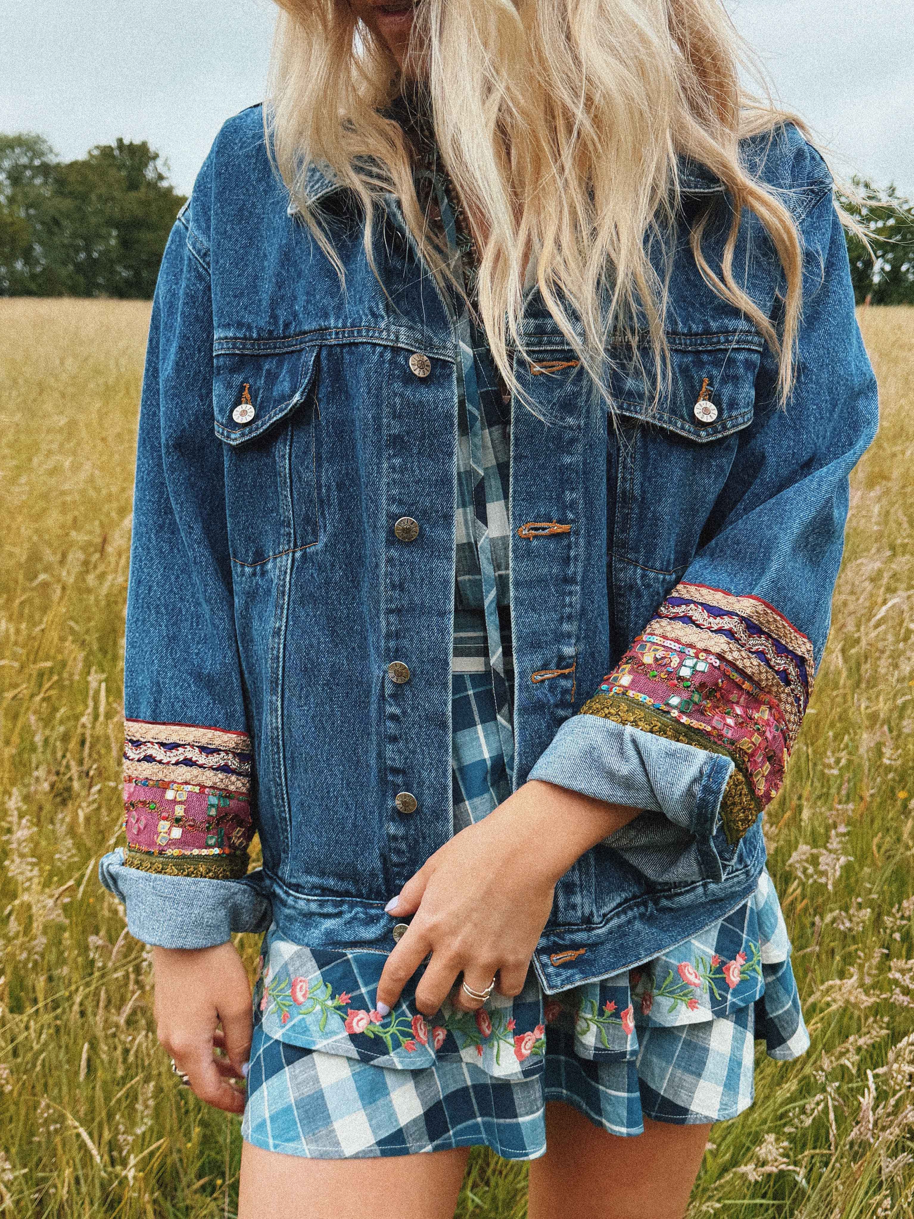 Dark blue denim jacket featuring a colourful embroidered decorative sleeve cuffs. front view