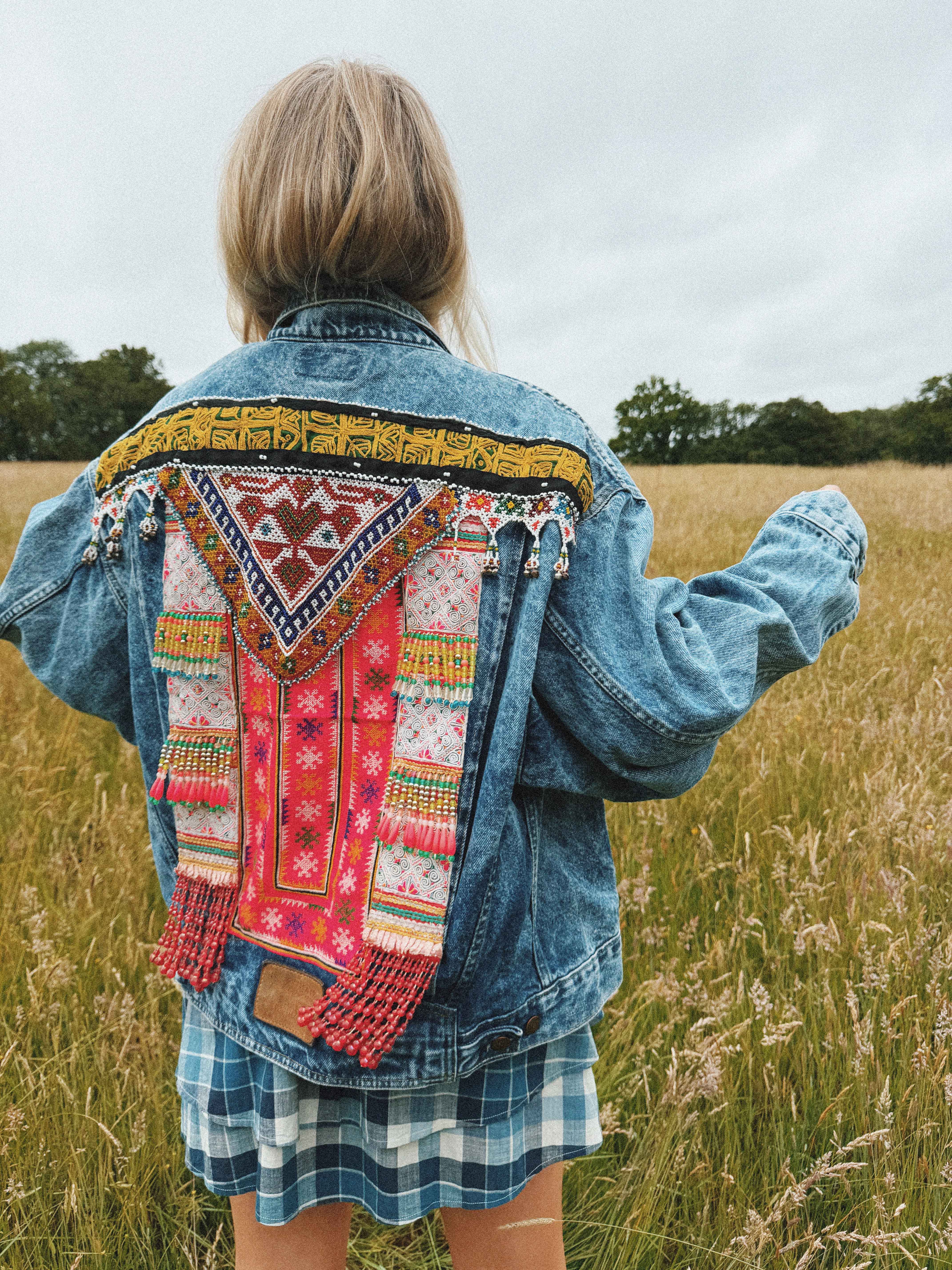 Bohemian-style blue denim jacket with colourful embroidered back detail, shown from the back.
