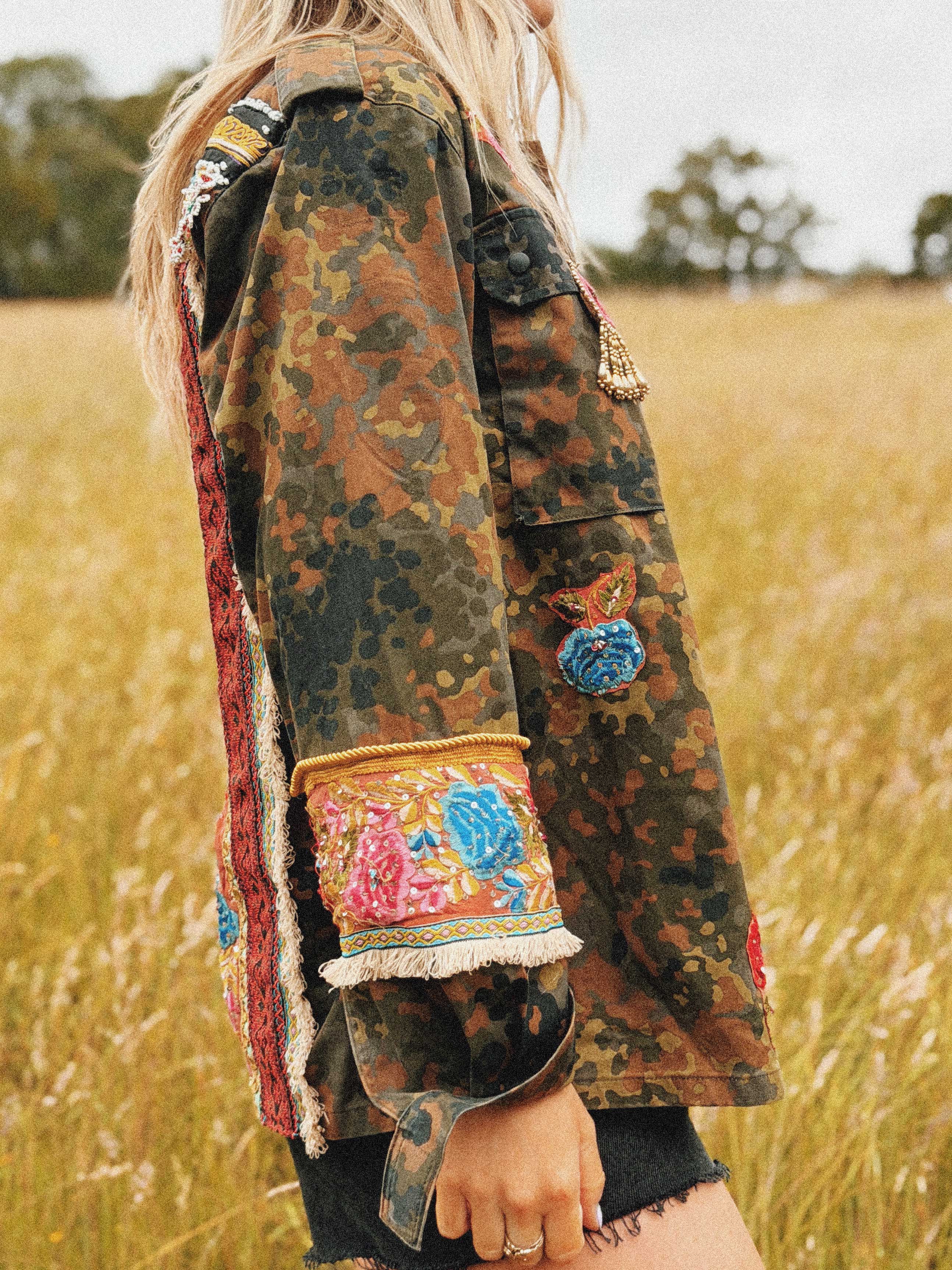 Embellished camouflage jacket with colourful embroidered back panel and embroidered sleeve cuffs, shown from the side.