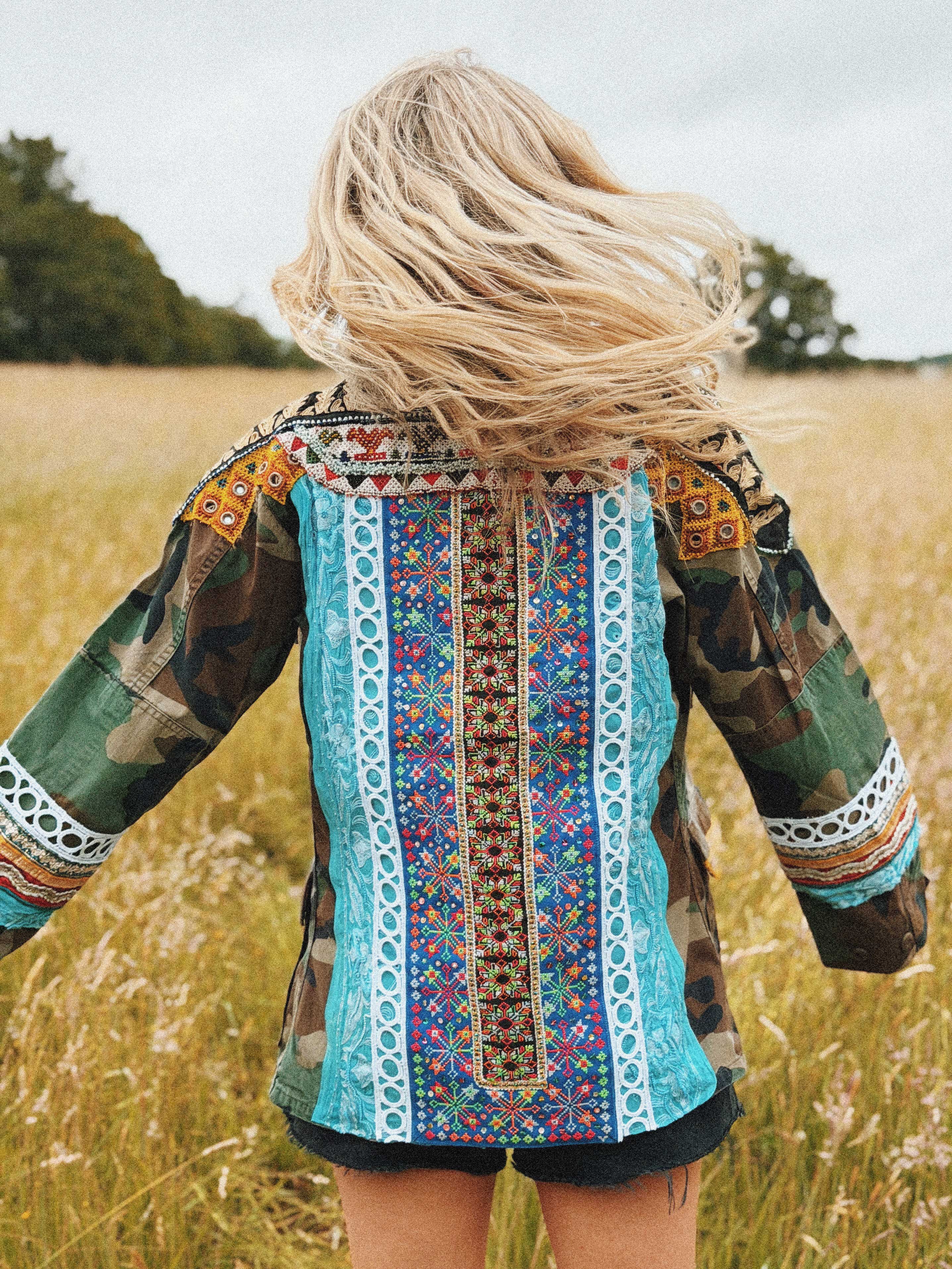 Camouflage jacket with colourful embroidered back panel and embellished trim, shown from the back.