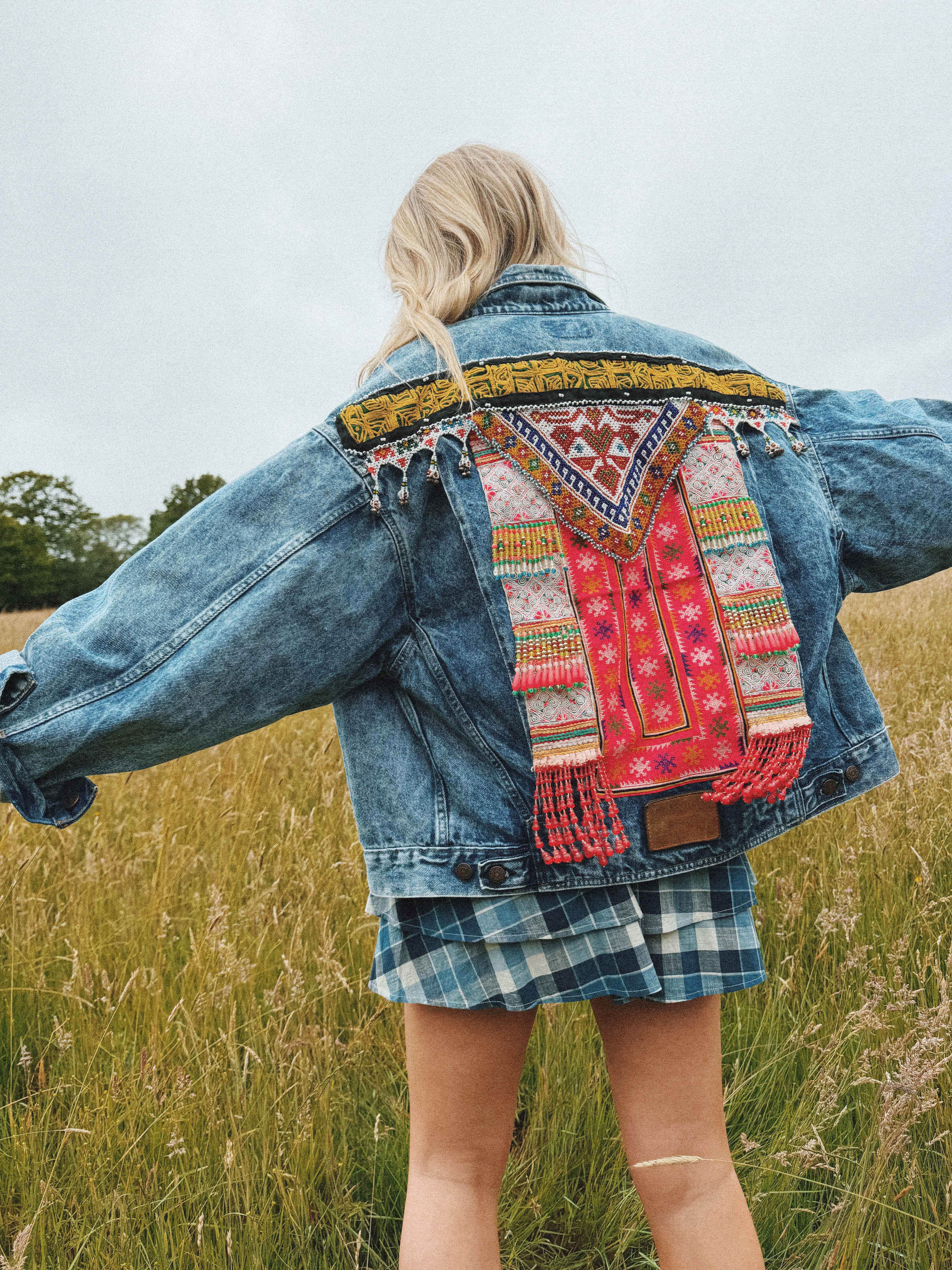 Bohemian-style blue denim jacket with colorful embroidered back detail, shown from the back.