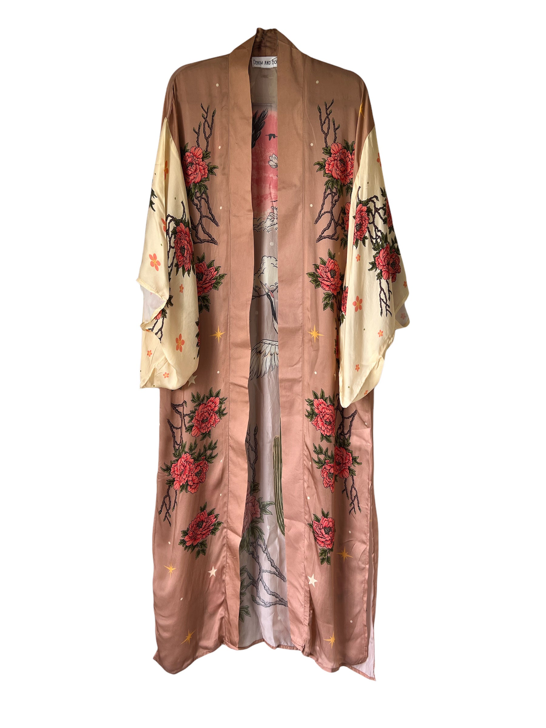 front view of a blush pink kimono-style robe featuring soaring cranes, towering cacti, blooming flowers, an eagle, and a red sun graphic.