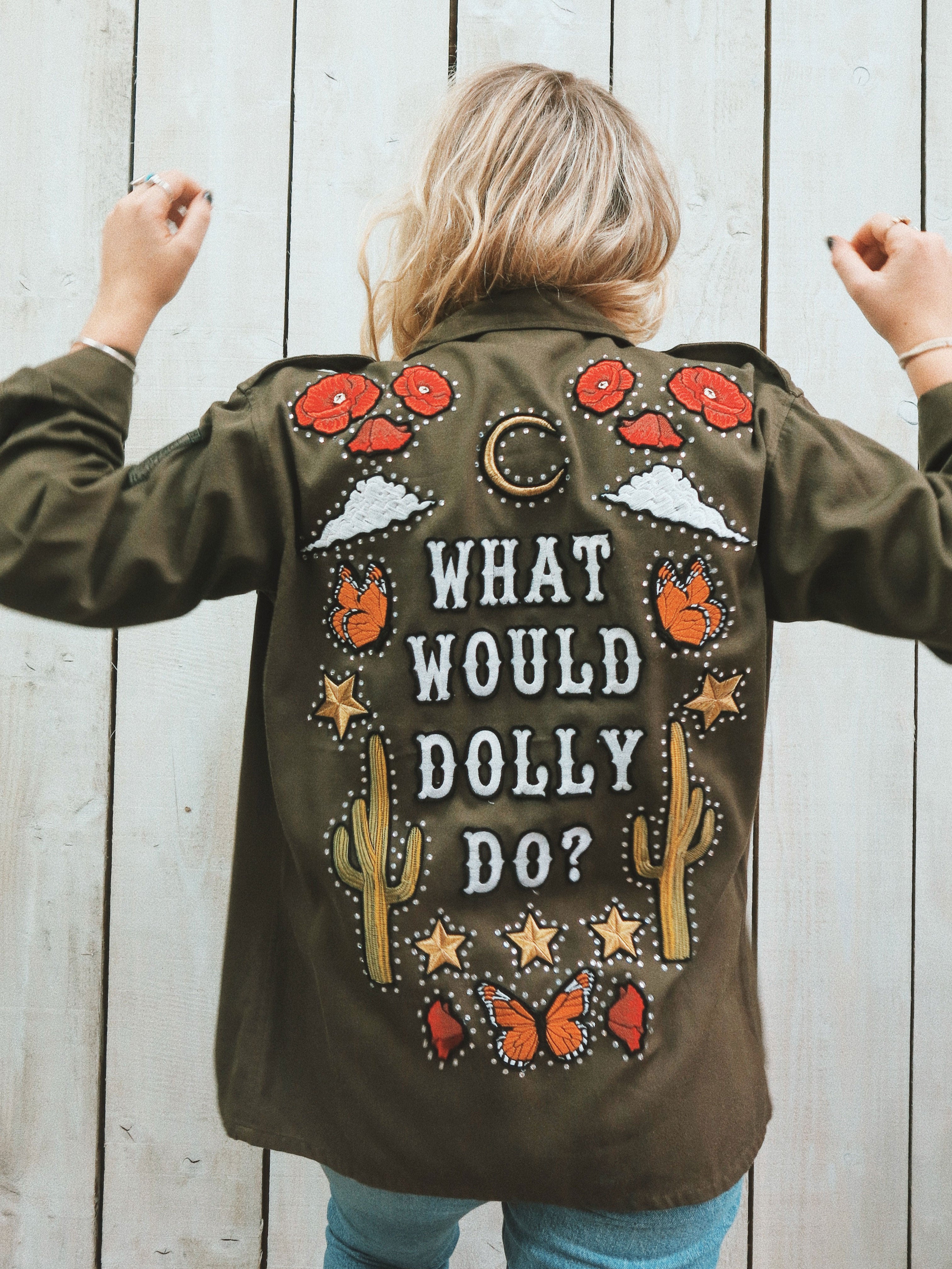 Back view of the What Would Dolly Do vintage khaki army jacket styled with blue jeans, featuring western-inspired embroidery, butterflies, cacti and rhinestones.