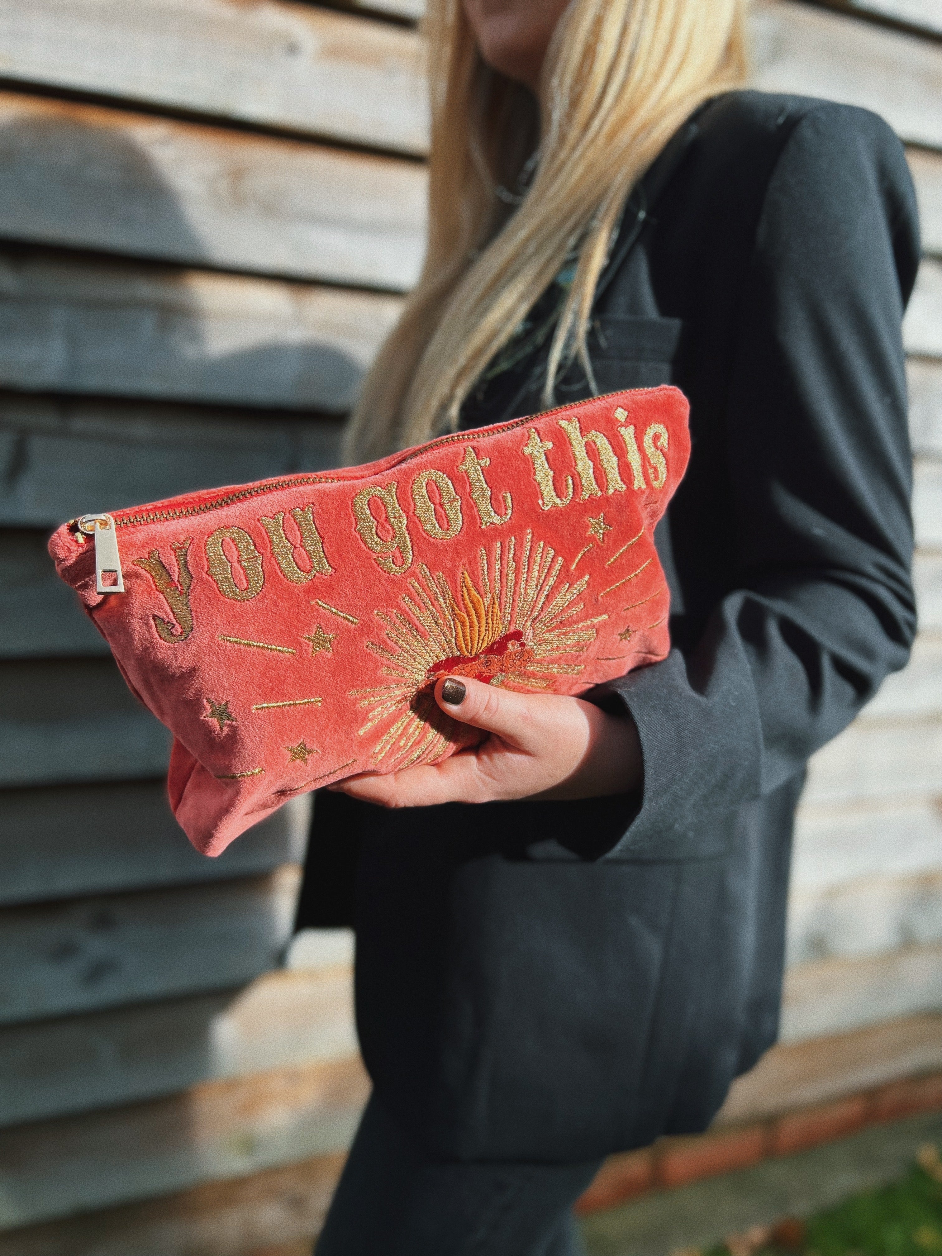 Person holding a rich pink velvet zip pouch embroidered with the phrase "you got this" and a radiant sacred heart design.