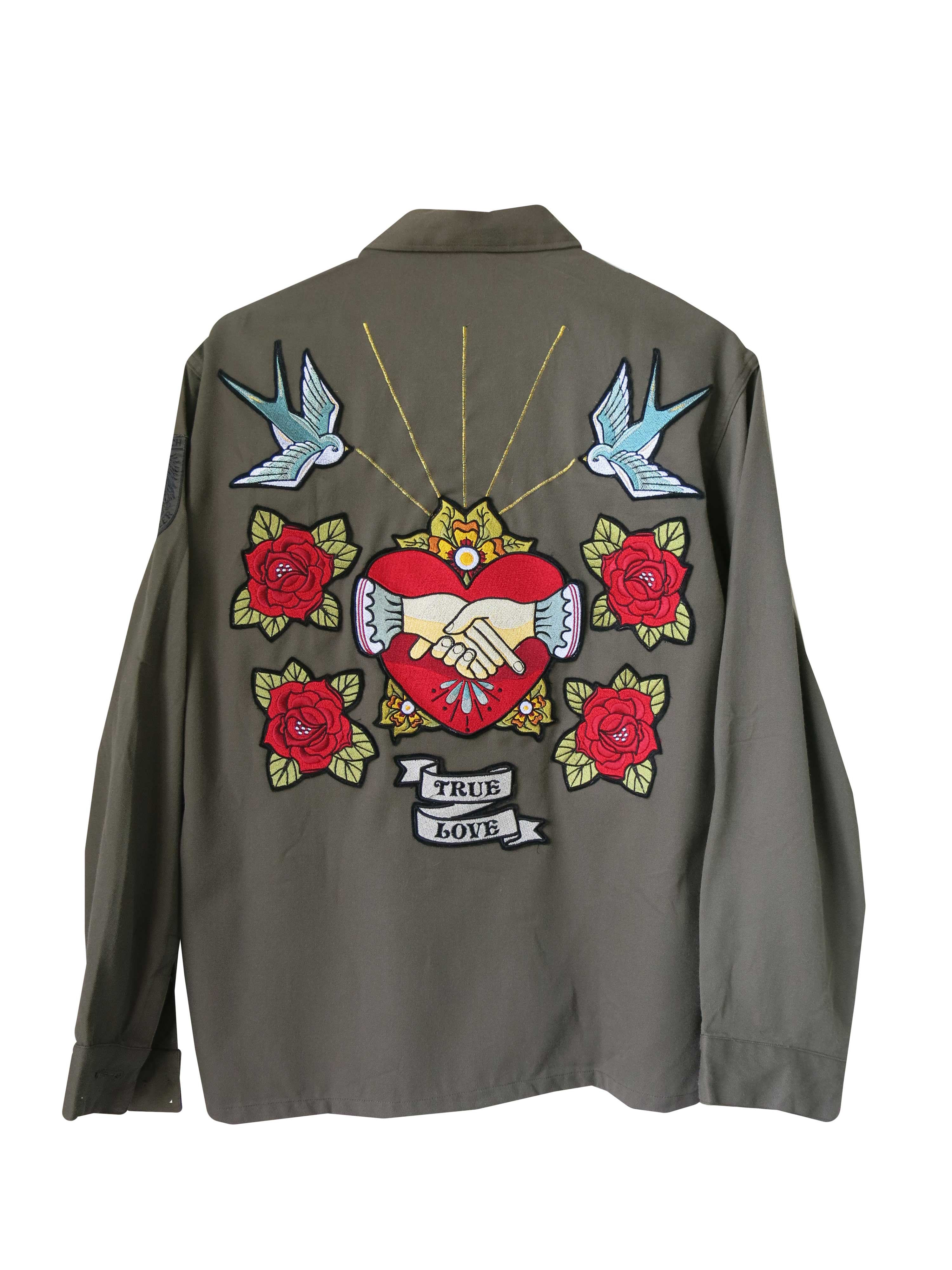 Olive green military jacket with a large embroidered back design featuring clasped hands inside a heart, swallows, roses, and the words "TRUE LOVE."
