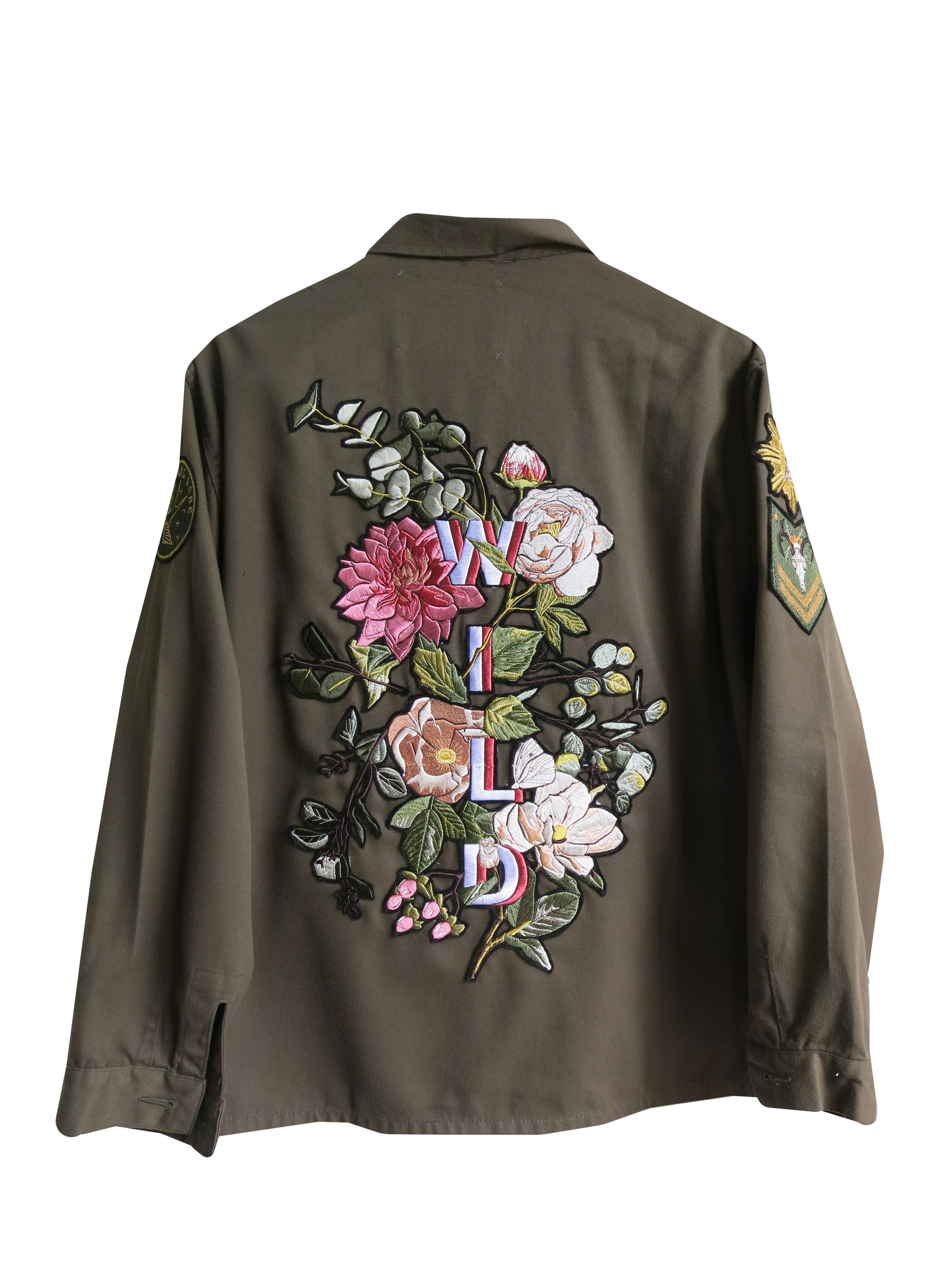 Olive green jacket with colourful floral embroidered back design and "WILD" lettering, back view.