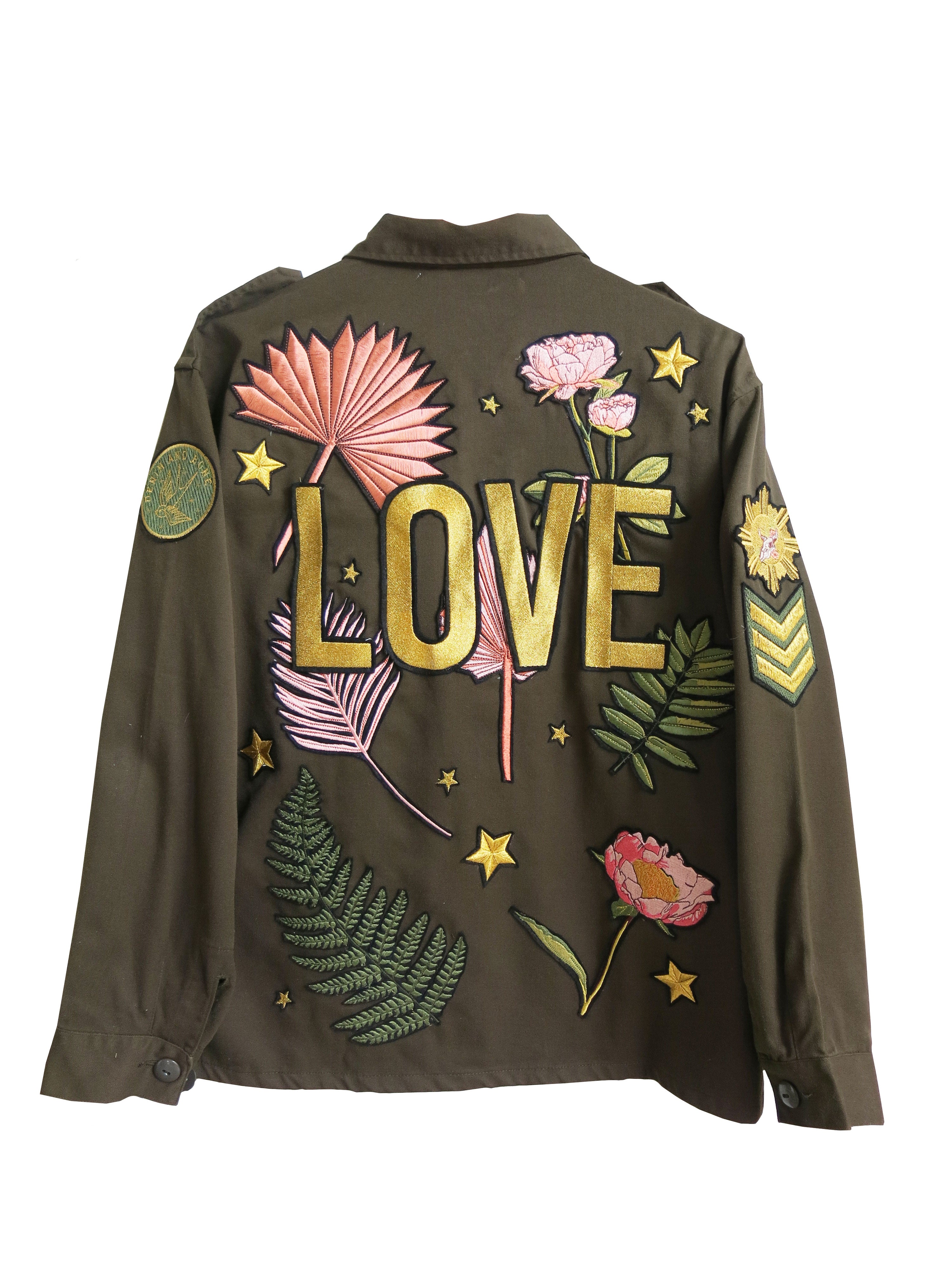 Back view of an olive green military jacket with floral embroidered design and "LOVE" lettering.