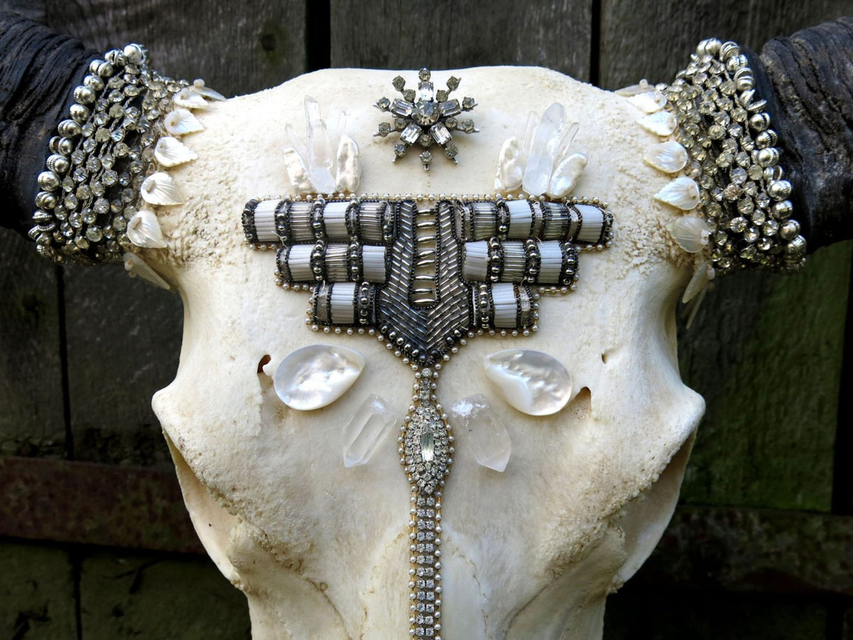 Close-up of decorative Thai buffalo skull showcasing detailed silver crystal beadwork, shell embellishments, and geometric tribal-inspired design across the forehead.