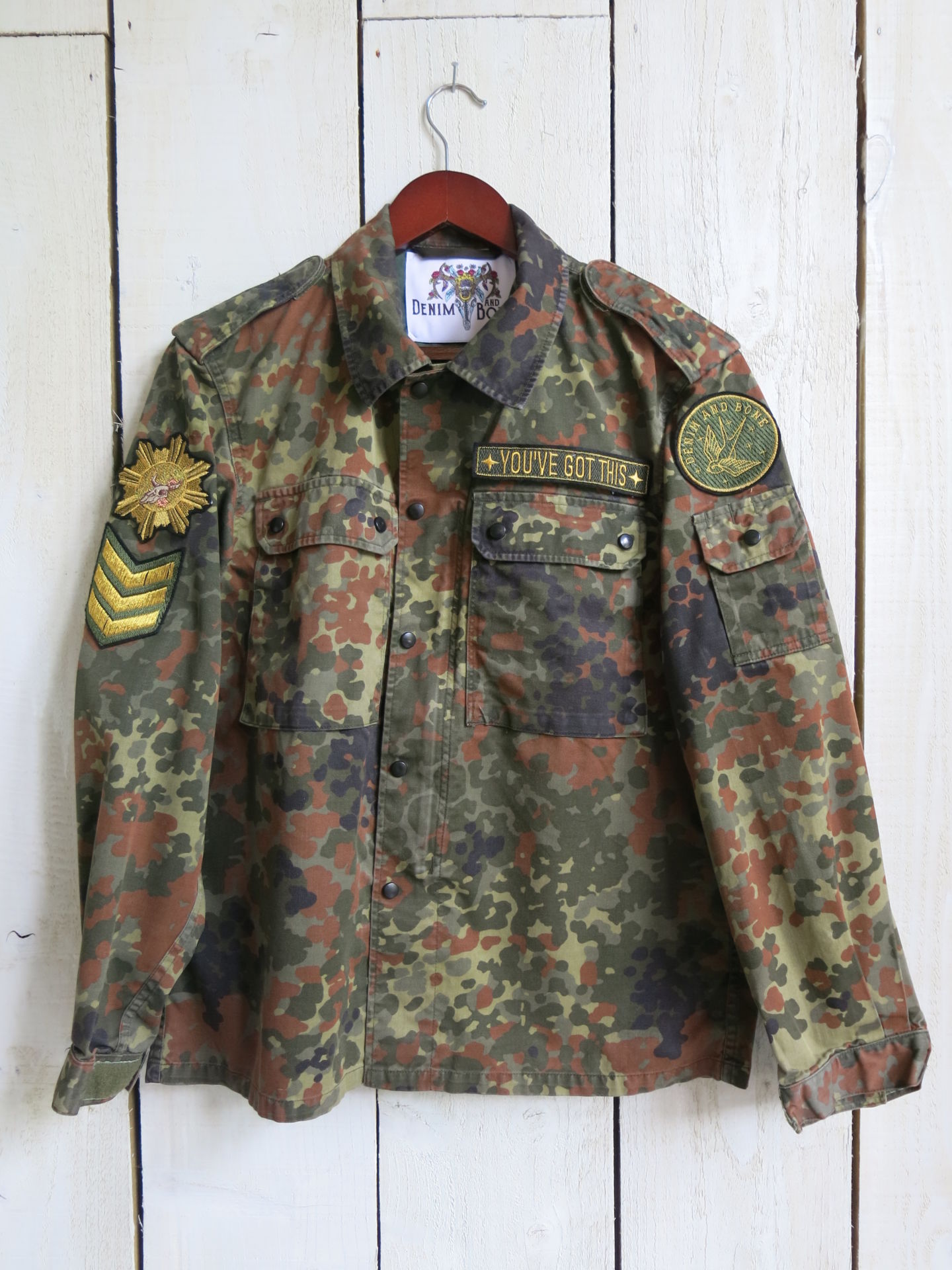 Camouflage military jacket with decorative patches and "YOU'VE GOT THIS" chest embroidery, front view.