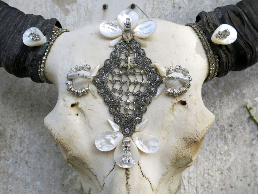 Close-up of a decorative Thai buffalo skull showcasing intricate silver bead embroidery, freshwater pearls, shell details, and crystal embellishments.
